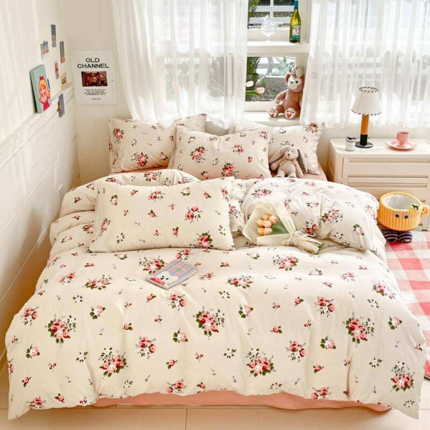 Blumenbettwäsche auf einem ordentlich gemachten Bett in einem hellen, gemütlichen Schlafzimmer mit Kuscheltieren, einem Nachttisch und einem Fenster mit transparenten Vorhängen.