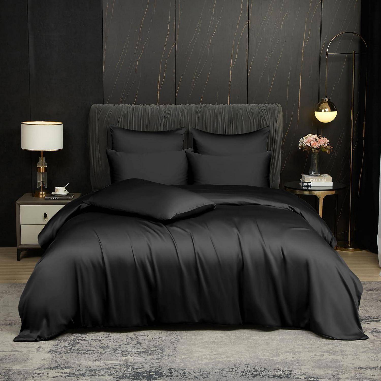Schwarze Bettwäsche auf einem ordentlich gemachten Bett in einem dunklen, eleganten Schlafzimmer mit passenden Kissen, Nachttischlampen und Akzenttischen.