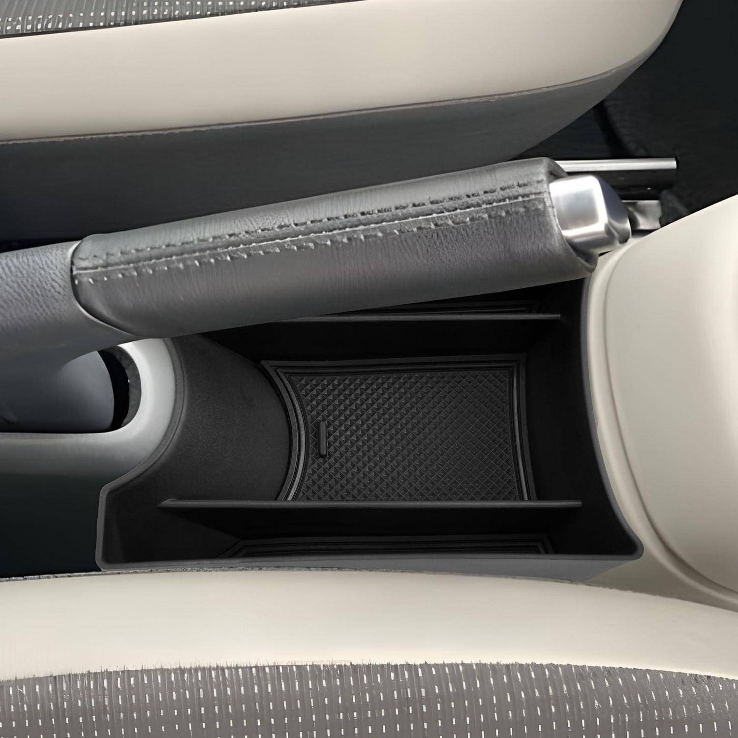 Mittelkonsole des Autos mit Handbremse und kleinem Ablagefach zwischen beigen Sitzen, das ein leeres Fach für Gegenstände zeigt.