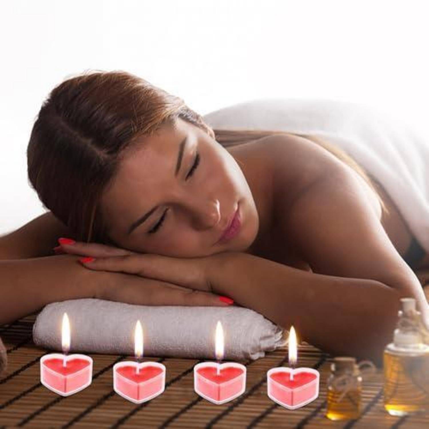 Frau, die mit dem Gesicht nach unten auf einem Massagetisch liegt, mit Kerzen und Massageölen, was eine Spa- oder Entspannungsbehandlung andeutet.