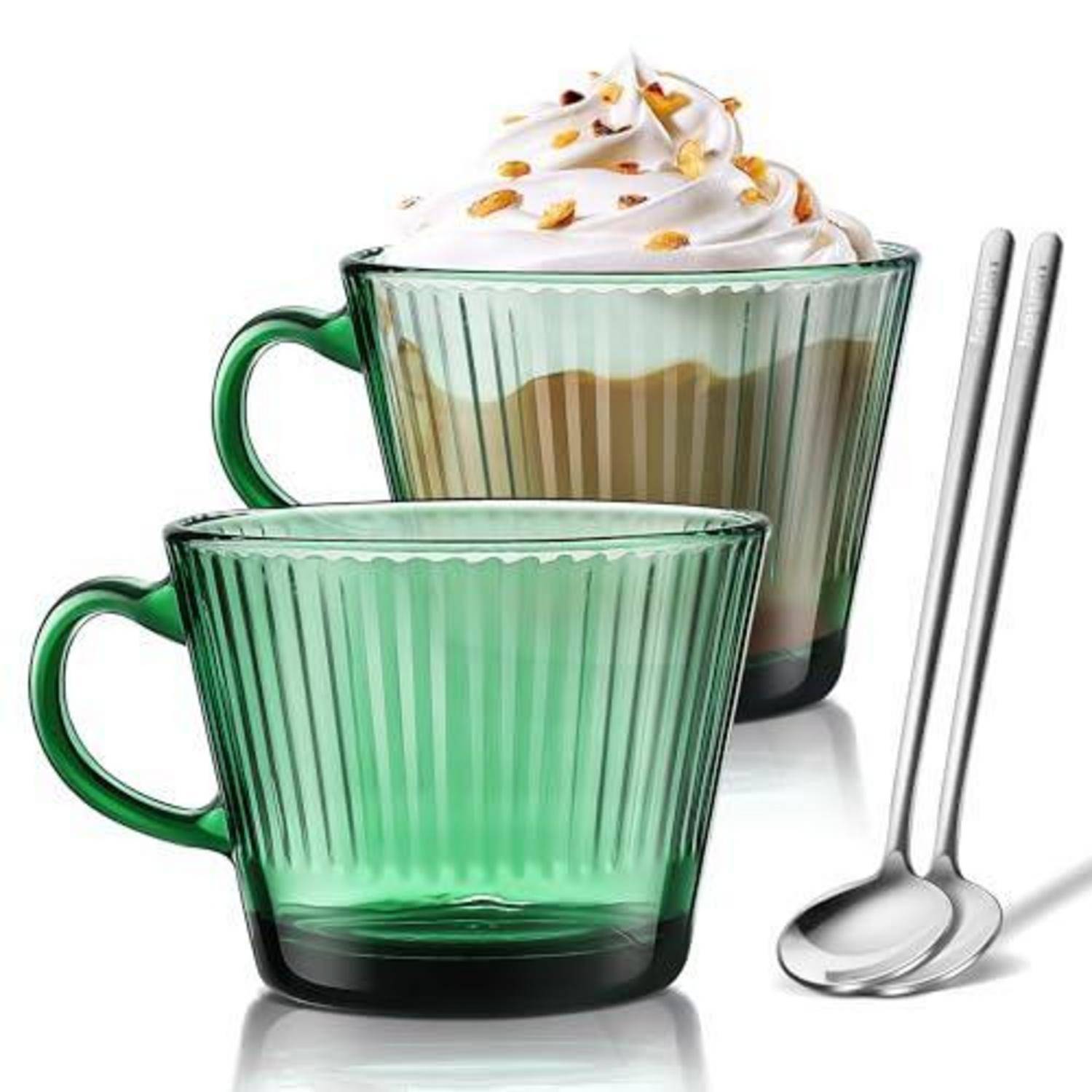 Zwei grüne gerippte Glastassen, eine gefüllt mit geschichtetem Kaffee, garniert mit Schlagsahne und Nüssen, mit zwei Edelstahlöffeln daneben.