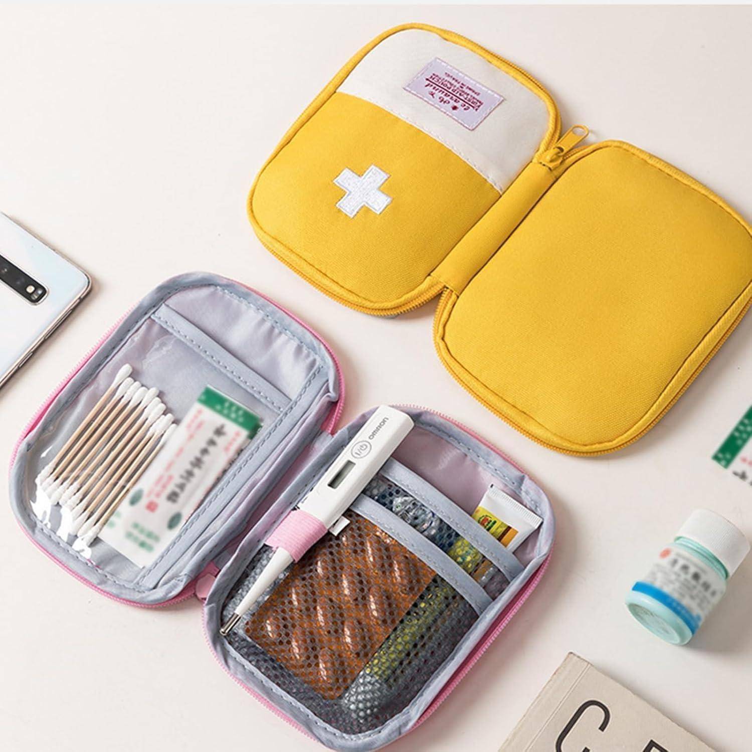 Offene gelbe und rosa medizinische Kits mit organisierten Erste-Hilfe-Materialien wie Wattestäbchen, Medikamente, Verbandsmull und einem Thermometer auf einem Tisch.
