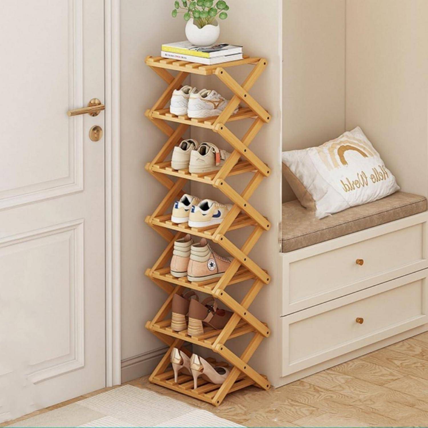 Holzharmonika-Schuhregal neben einer Bank, das mehrere Paar Schuhe hält und mit Büchern und einer kleinen Pflanze oben abgestellt ist.