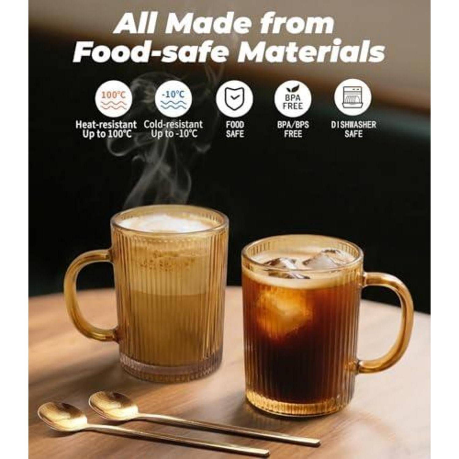 Anzeige mit zwei gerippten Glaskrügen mit Henkeln auf einem Tisch, einer mit heißem dampfendem Getränk und einer mit Eiskaffee, mit der Beschriftung „Alle aus lebensmittelsicheren Materialien" und Symbolen für hitzebeständig, kältebeständig, lebensmittelsicher, BPA-frei und spülmaschinenfest.