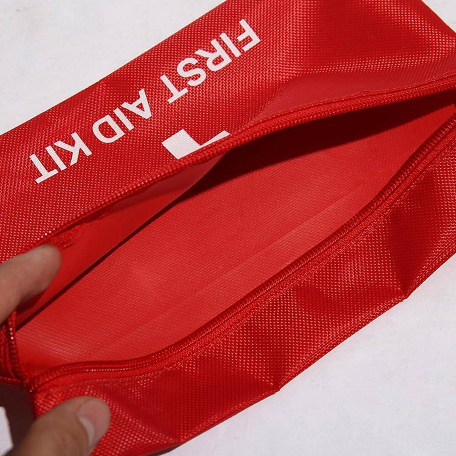 Rote Erste-Hilfe-Tasche mit Reißverschluss wird geöffnet und zeigt das leere Innere.