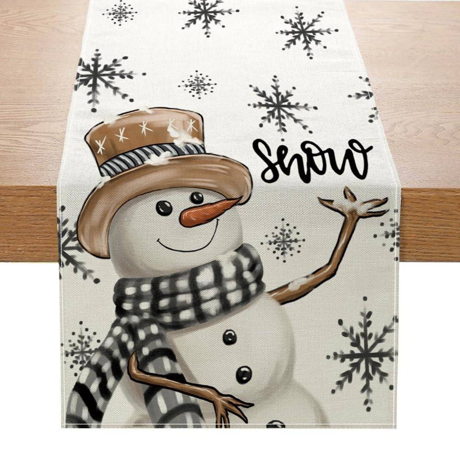 Dekorativer Wintertischläufer mit einem gemalten Schneemann, der einen Hut und einen Schal trägt, der neben dem Wort „Schnee