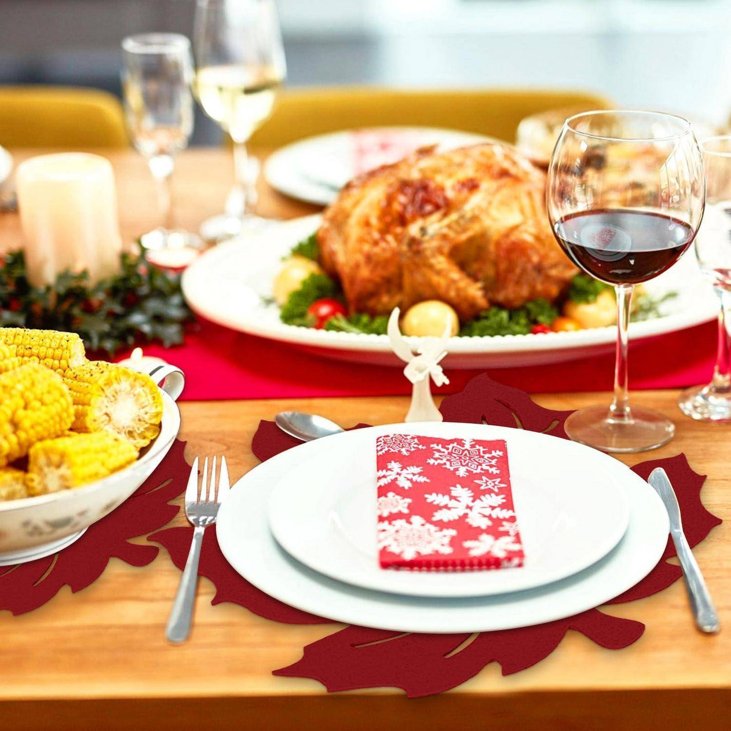 Festliches Thanksgiving-Abendessenstisch mit einem gebratenen Truthahn als Mittelpunkt, Mais, Weingläsern und einem Gedeck mit einer roten Serviette und weißem Schneeflocken-Design.