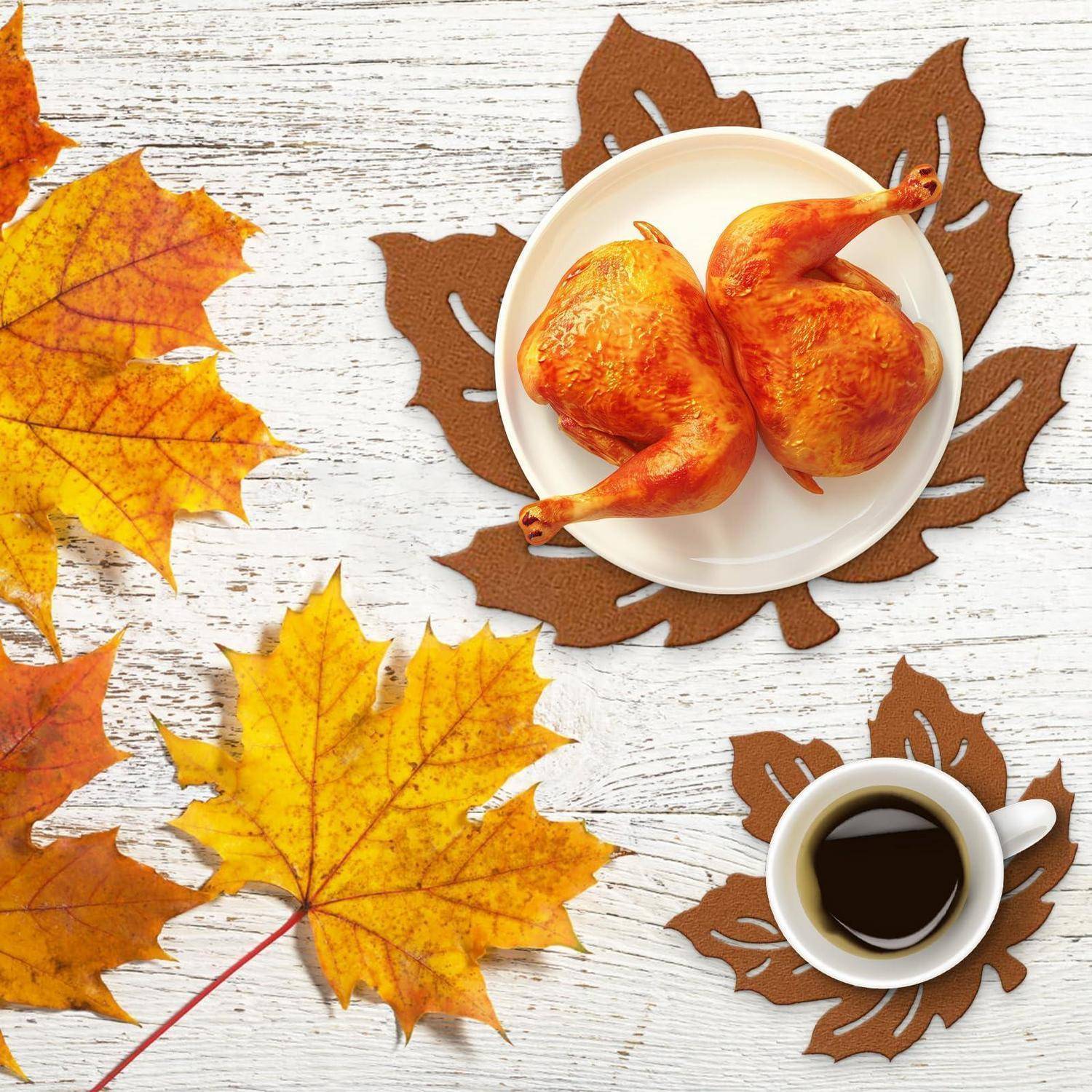Zwei gebratene Hähnchenkeulen auf einem weißen Teller, mit einer Tasse Kaffee und Herbstblättern auf einem weißen Holztisch.
