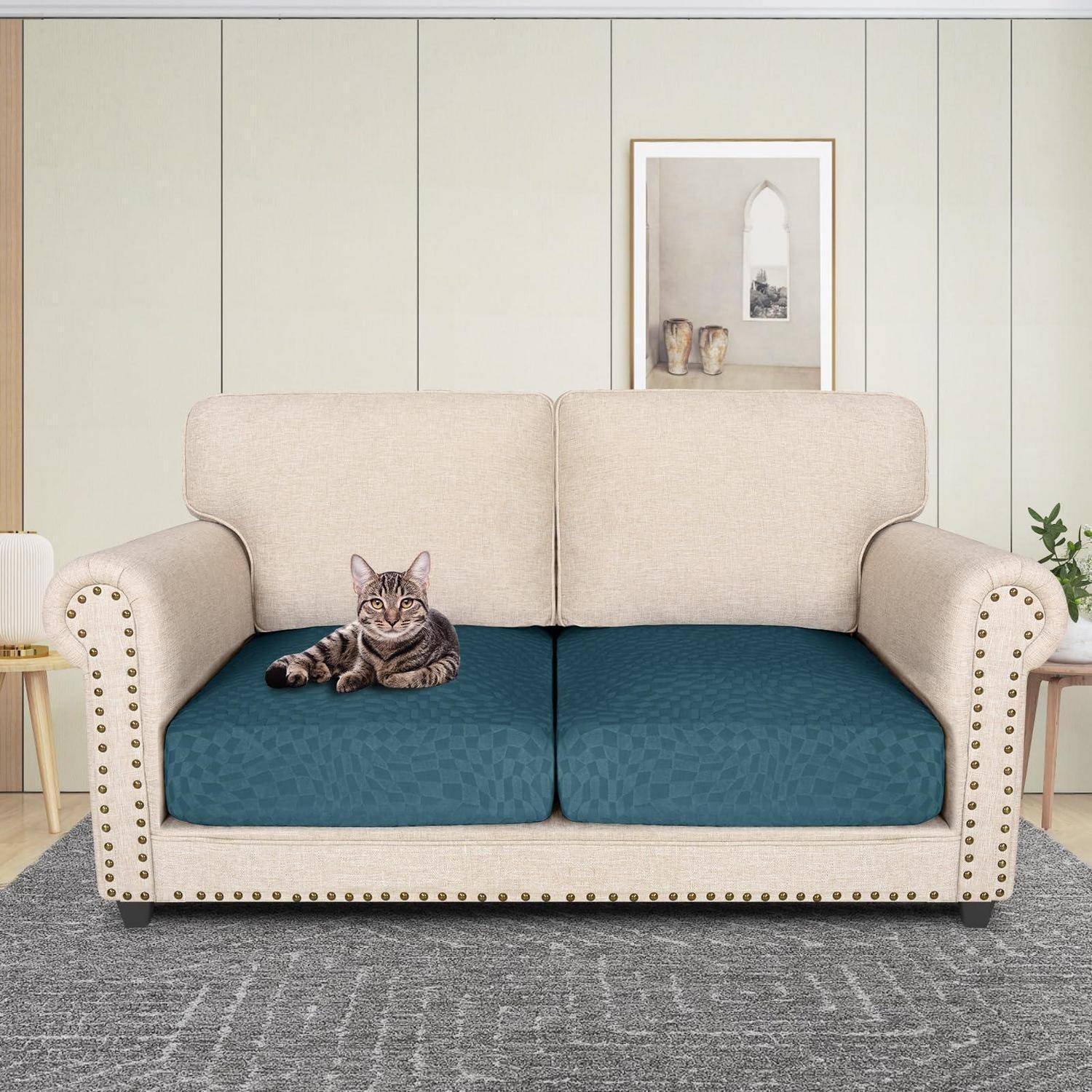 Getigerte Katze, die auf einer blaugepolsterten beigefarbenen Recamiere in einem Wohnzimmer liegt.