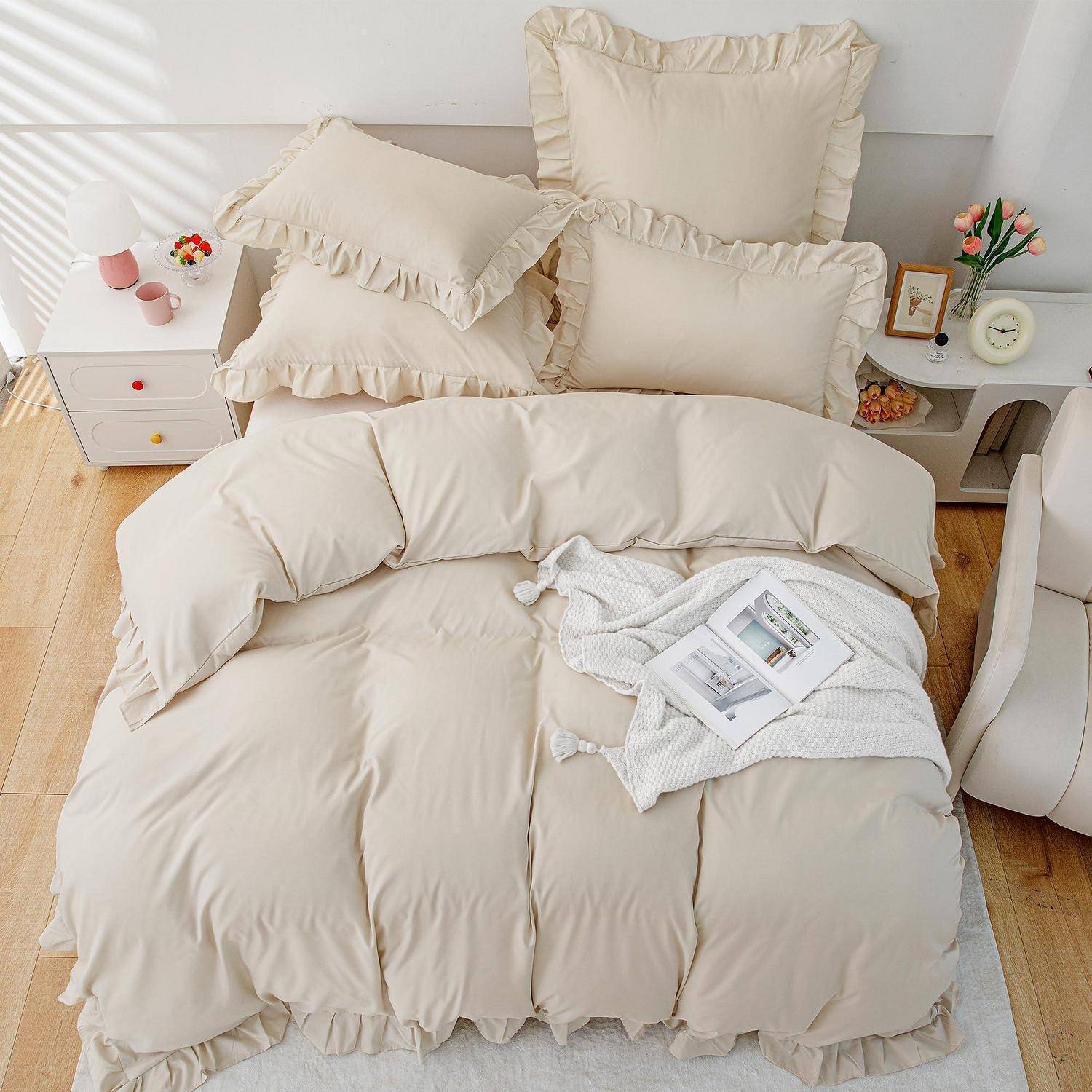 Ordentlich gemachtes Bett mit cremefarbenem Rüschenbezug, Kissen und einem Buch darauf in einem hellen, gemütlichen Schlafzimmer.