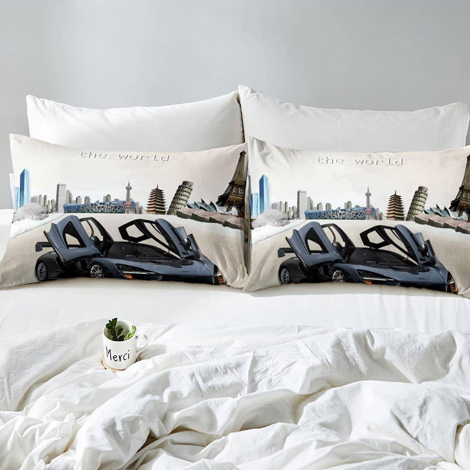 Ein ordentlich gemachtes weißes Bett mit zwei passenden dekorativen Kissen, bedruckt mit „der Welt" und einem schwarzen Sportwagen, sowie einem kleinen „Merci"" Blumentopf auf der Decke.
