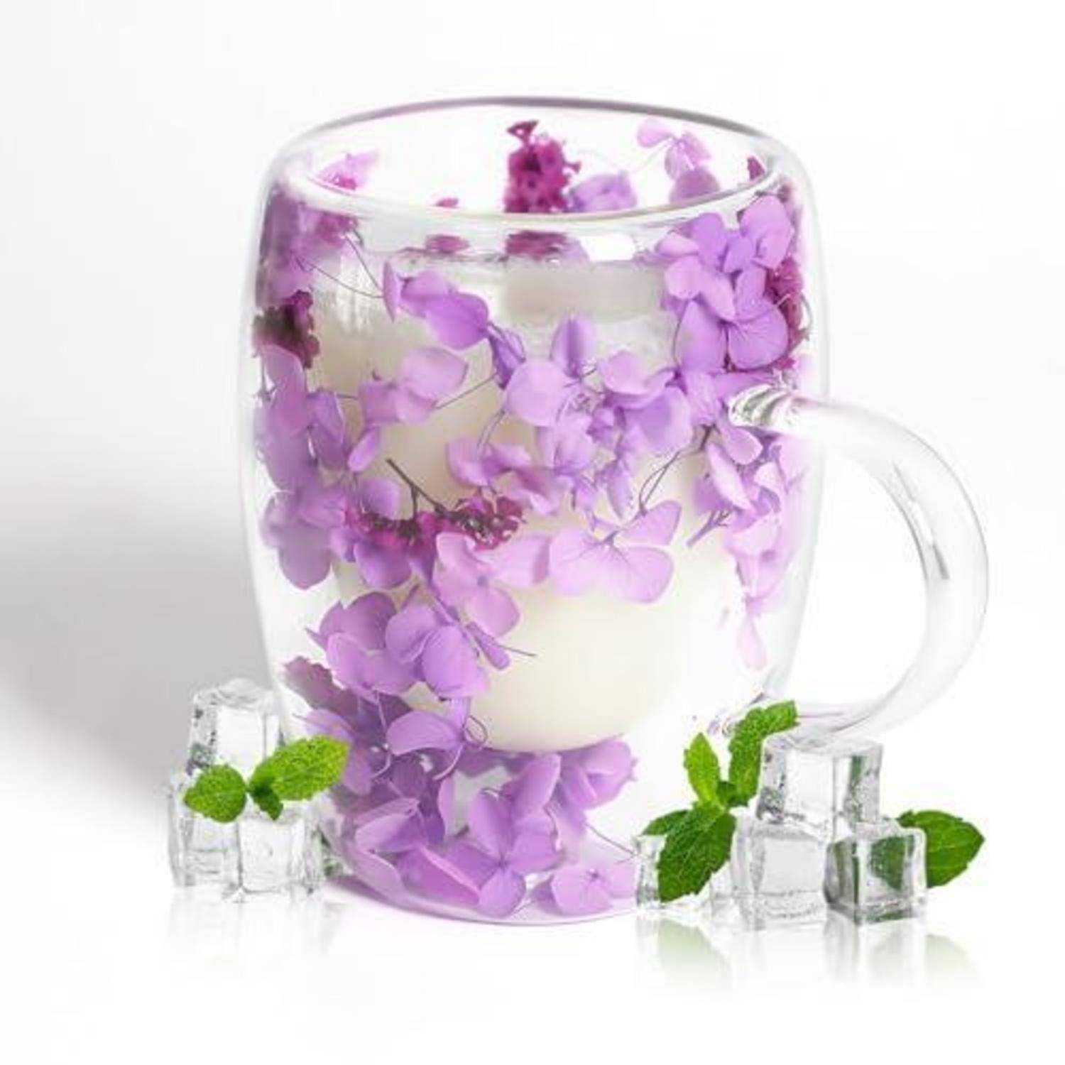 Glastasse gefüllt mit Wasser, eine weiße Kerze und schwebende violette Blüten, mit Eiswürfeln und Minzweigun daneben auf weißem Hintergrund.