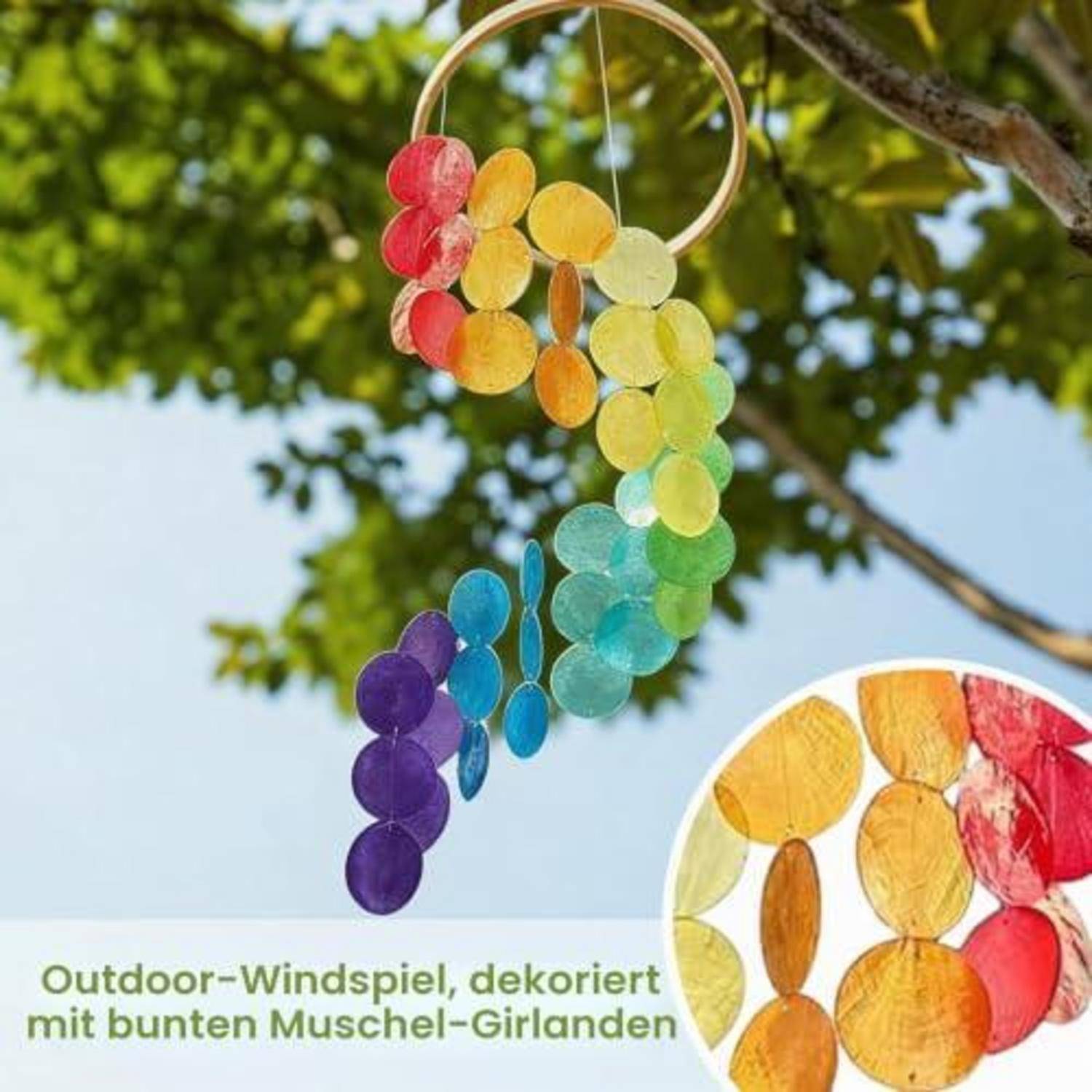 Bunte Windspiele aus Muschelscheiben hängen an einem Ring im Freien, mit regenbogenfarbigen Girlanden und deutschem Beschriftungstext.