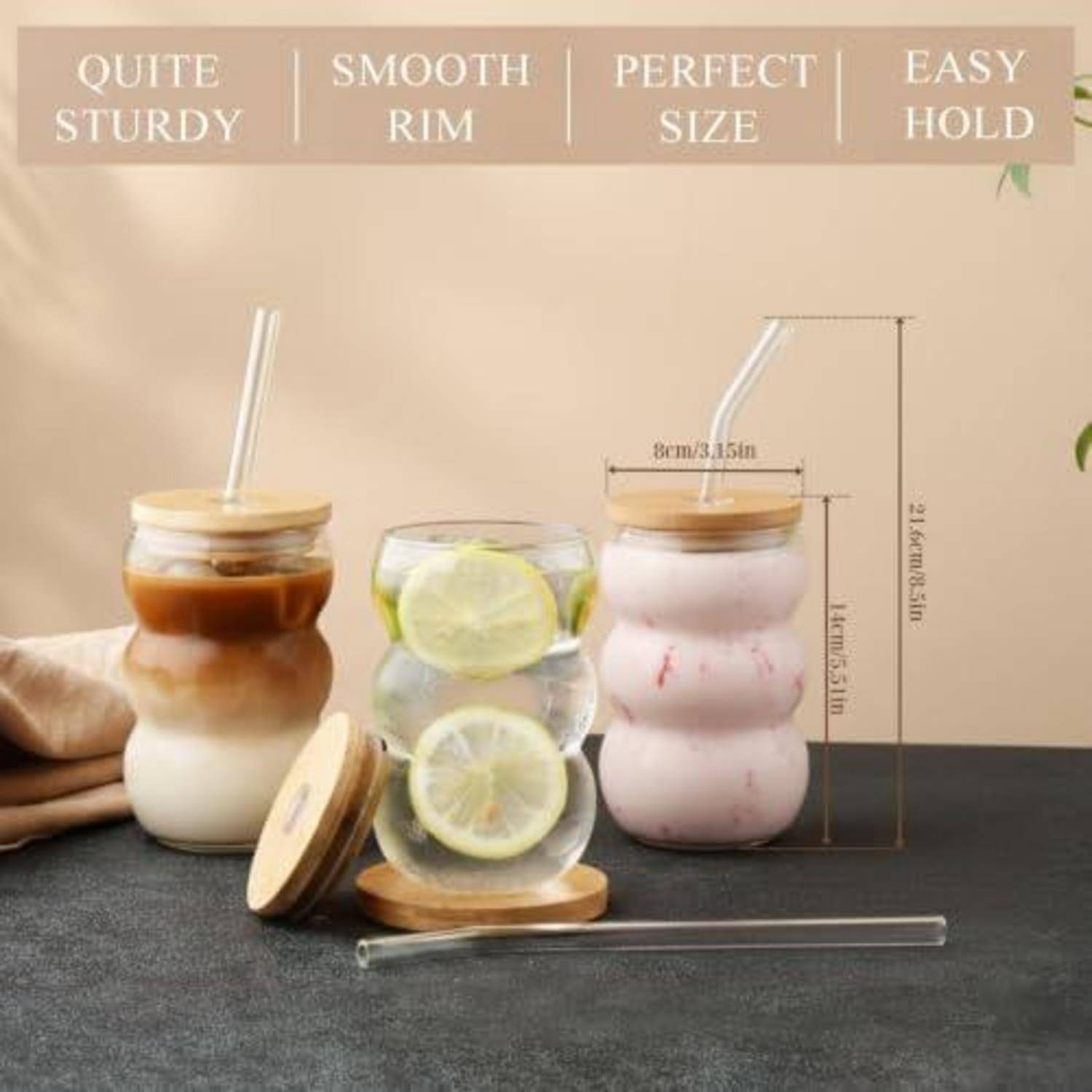 Produktfoto von drei strukturierten Glastassen mit Bambusdeckeln und Strohhalmen, beschriftet mit „Ziemlich robust", „Glatter Rand"", „Perfekte Größe"" und „Leicht zu halten"".