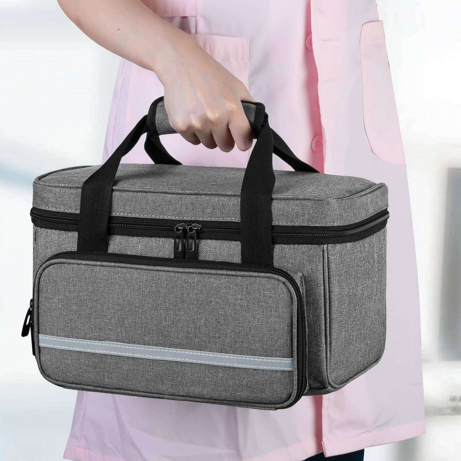 Person, die eine graue isolierte Lunchbox mit schwarzen Henkeln und einer vorderen Reißverschlusstasche hält.