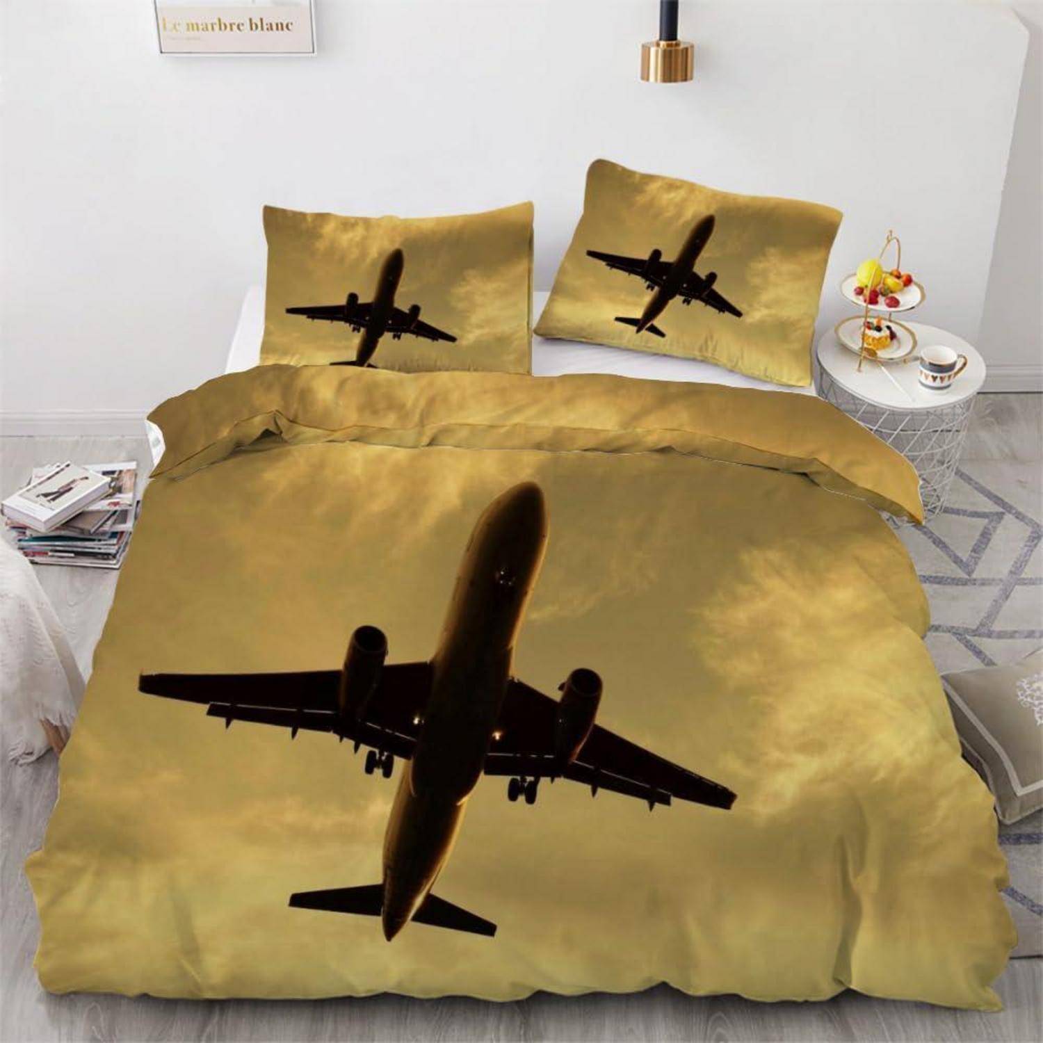 Flugzeug-Design Bettwäsche-Set mit großer Düsenflugzeug-Silhouette auf einem goldenem Bettdeckenbezug und zwei passenden Kissenbezügen in einem minimalistischen Schlafzimmer.