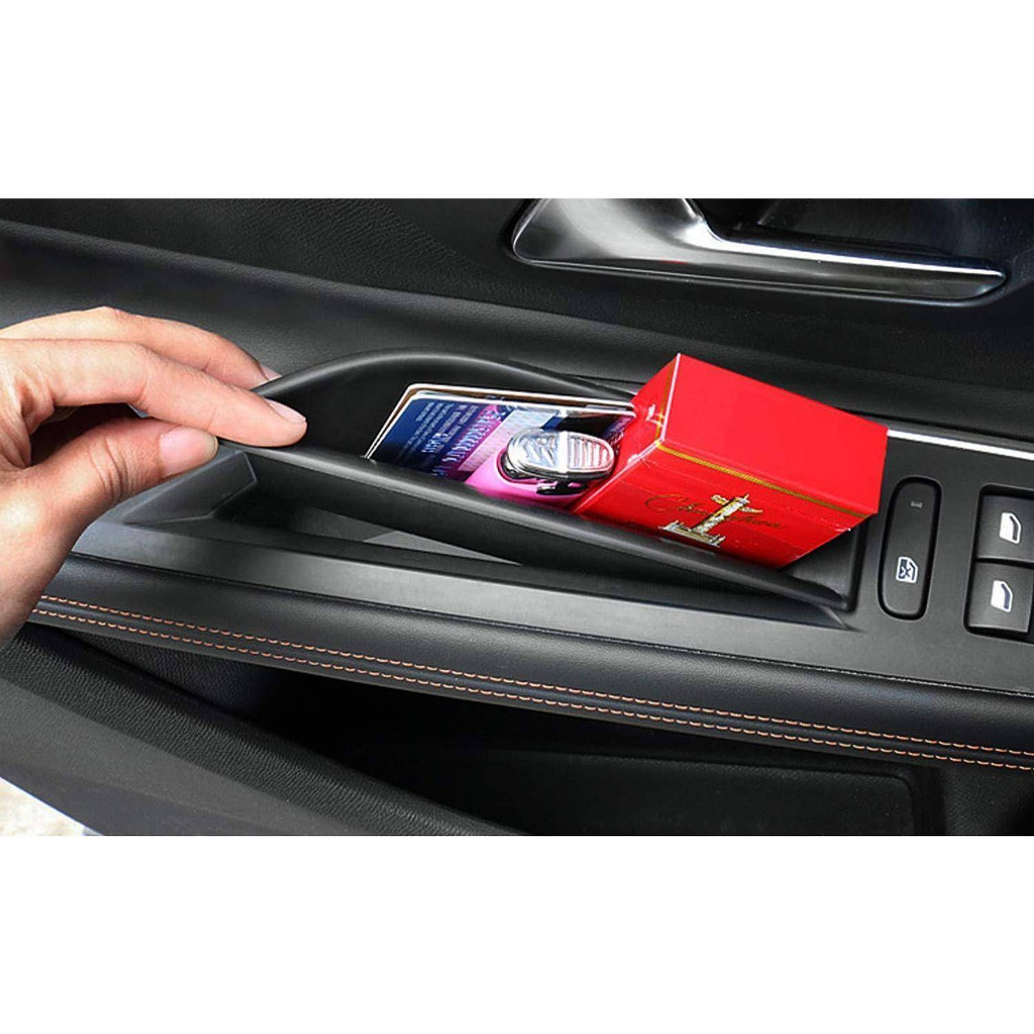 Eine Hand benutzt eine Autotürablagefach und hält eine rote Box, ein Telefon und ein kleines Gerät.