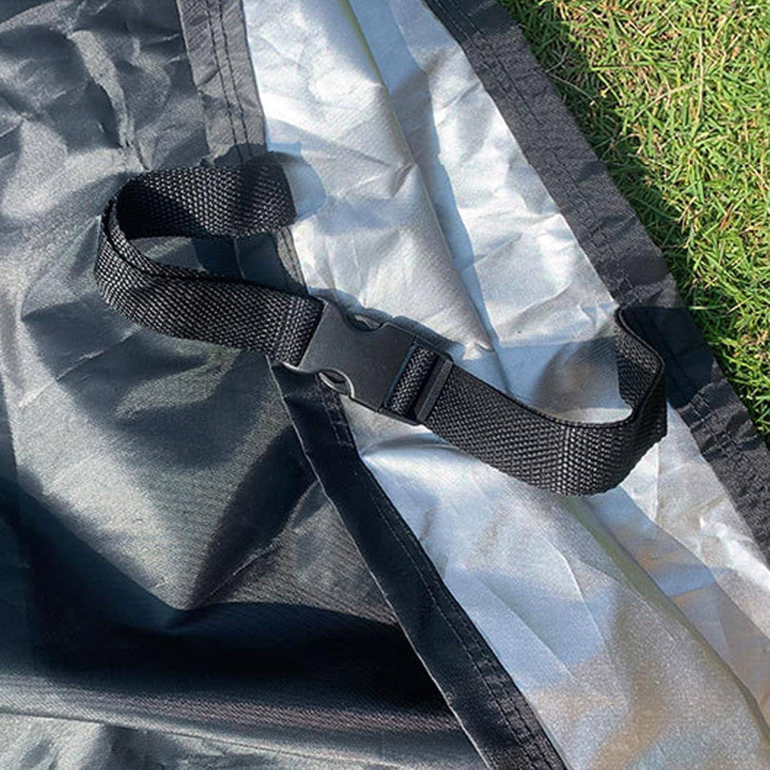 Nahaufnahme eines schwarzen verstellbaren Riemens und einer Schnalle, die an einer silbern-schwarzen Stoff-Matte oder Plane auf Gras befestigt sind.