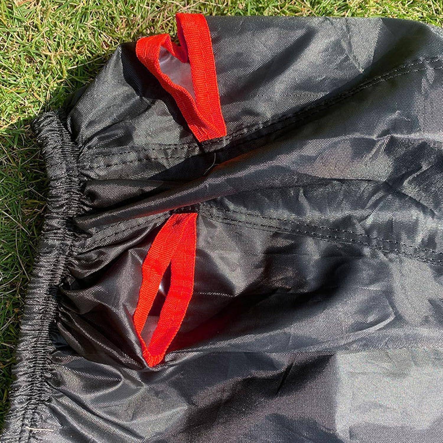 Nahaufnahme einer schwarzen Nylontasche oder Abdeckung, die auf Gras liegt, mit zwei sichtbaren roten Stoffschleifen.