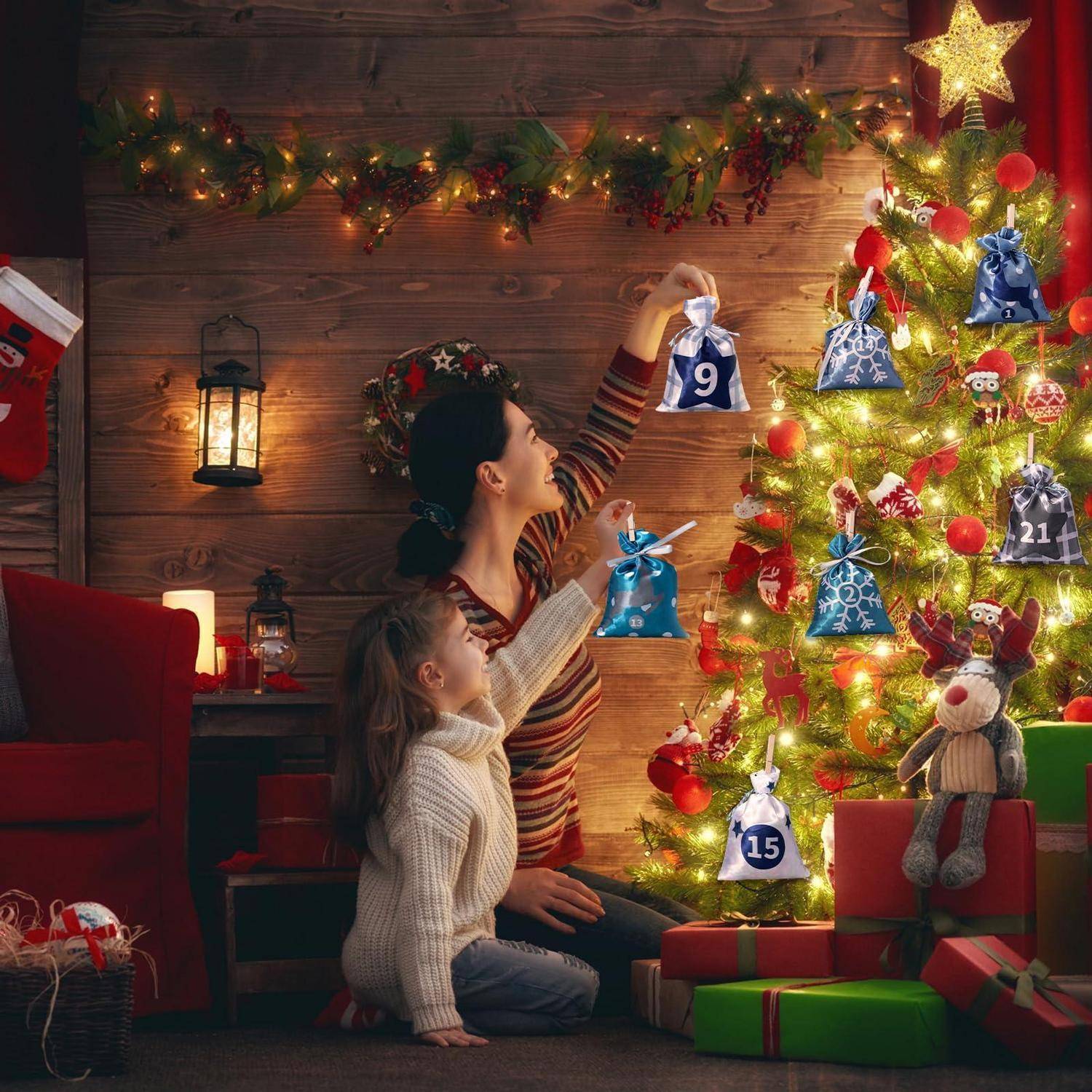 Frau und Kind platzieren nummerierte Adventskalender-Säckchen an einem geschmückten Weihnachtsbaum mit eingewickelten Geschenken darunter.