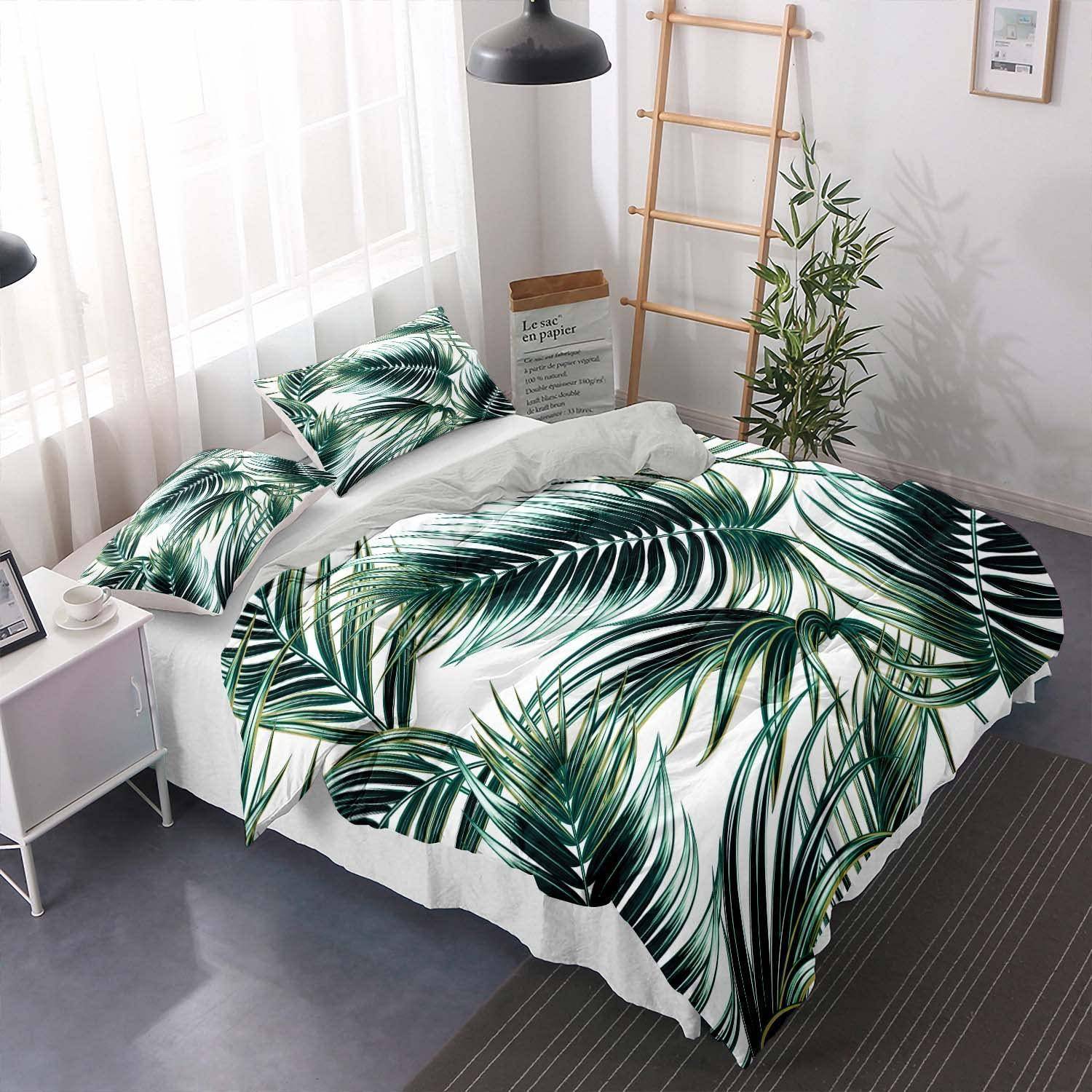 Ein ordentlich gemachtes Bett mit weißer Bettwäsche und grüner tropischer Blatt-Steppdecke in einem hellen, minimalistischen Schlafzimmer mit einem Nachttisch, einer Lampe, einem Leiternregal und einer Pflanze.