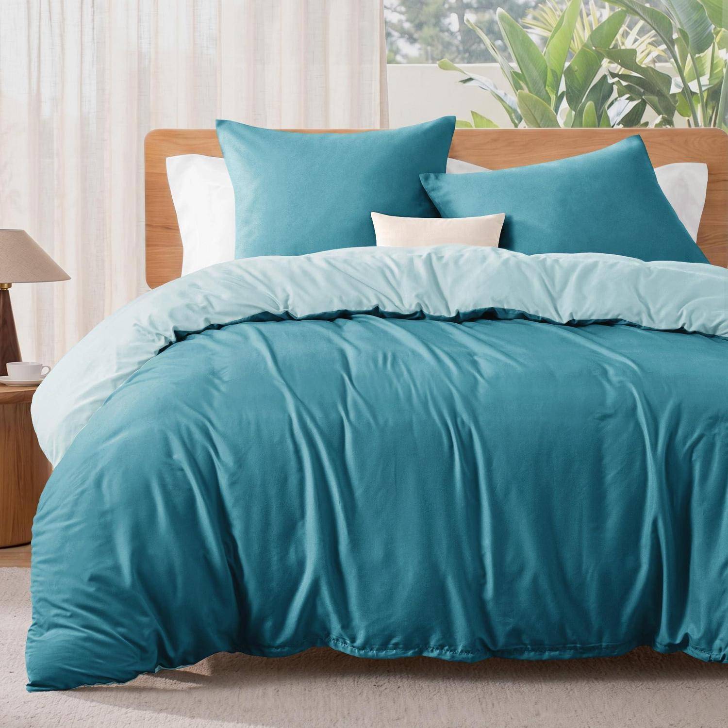 Ein ordentlich gemachtes Bett mit einer türkisfarbenen Bettdecke und passenden Kissen in einem hellen Schlafzimmer.