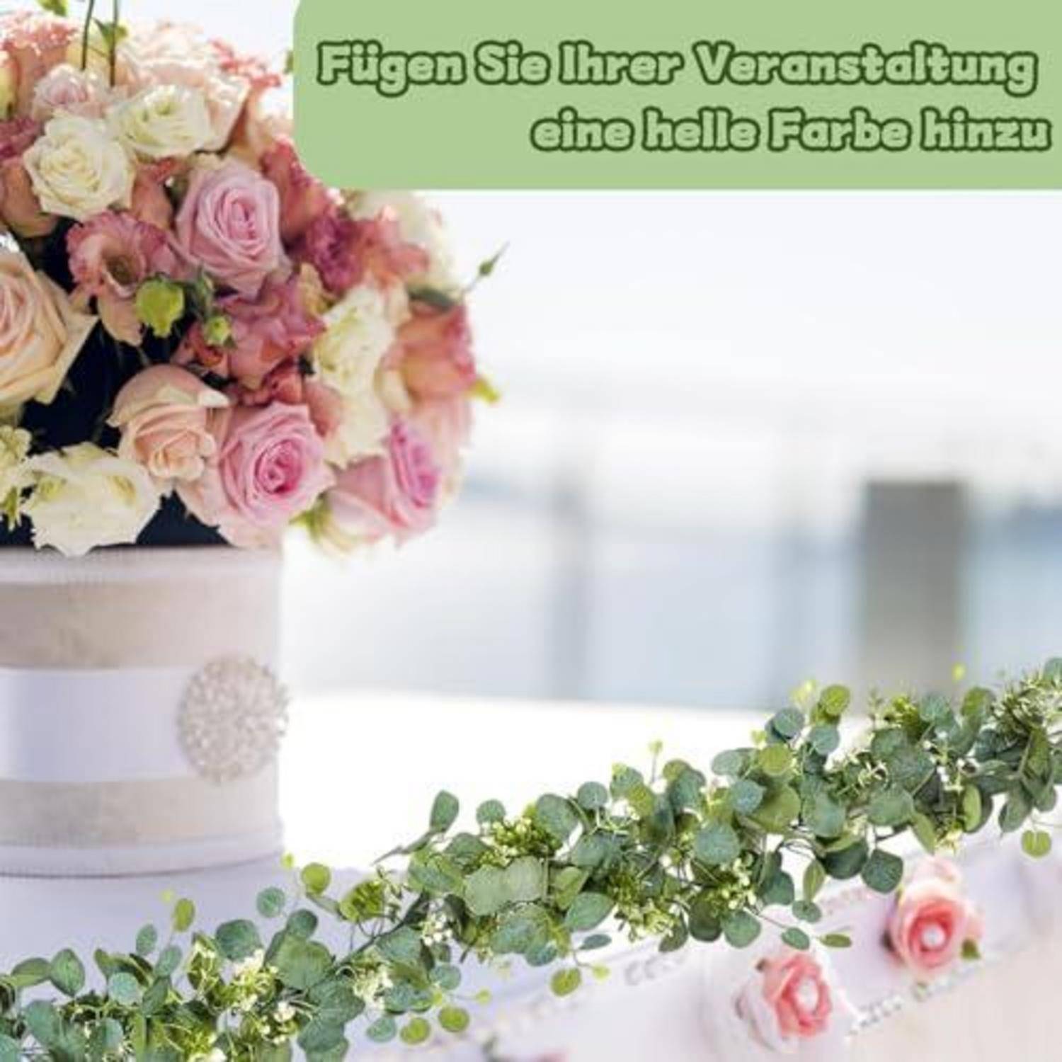 Ein dekorierter weißer Veranstaltungskuchen mit rosa und cremefarbenen Blumen und grüner Eukalyptusgirlande; deutscher Text sagt „Verleihen Sie Ihrer Veranstaltung eine leuchtende Farbe".
