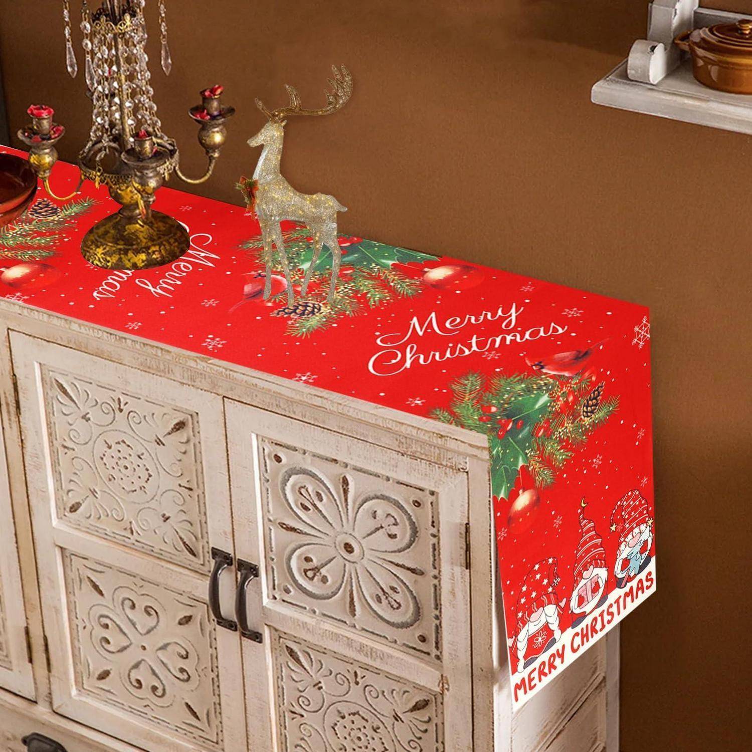 Weihnachtliches Sideboard mit rotem "Frohe Weihnachten""-Tuch, dekorativem Rentier und Kerzenhalter oben, was festliche Hausdekoration andeutet.