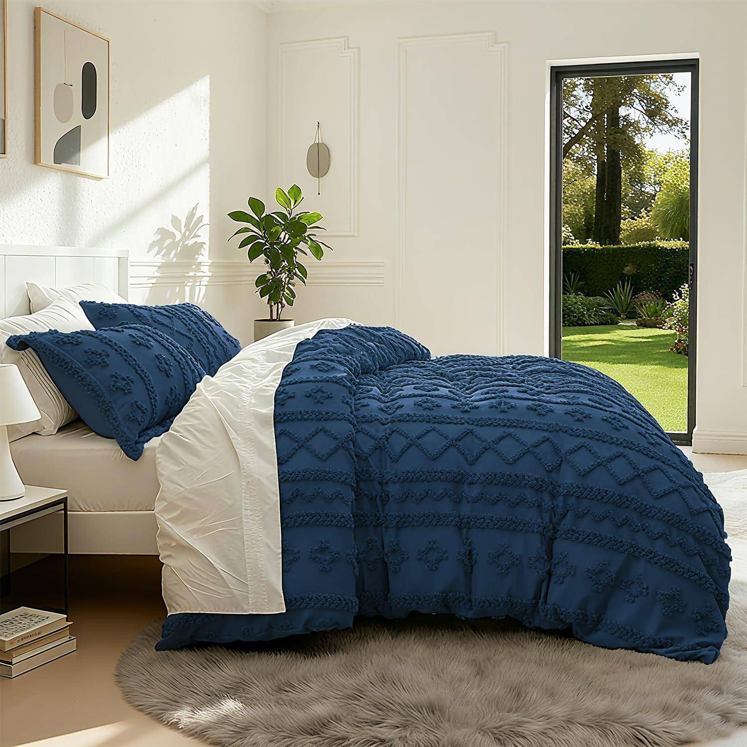 Helles Schlafzimmer mit einem Bett in blau-weißer Bettwäsche, einer Topfpflanze, Wandkunst und einer offenen Tür zu einem sonnigen Garten.