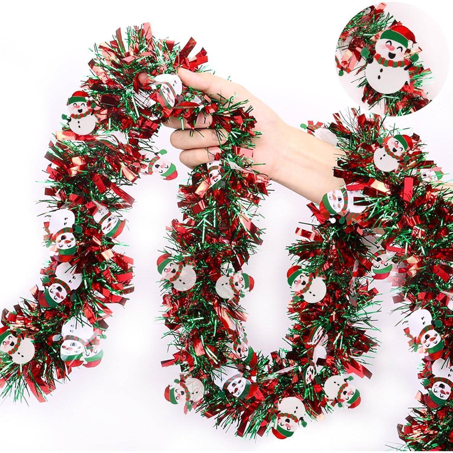 Eine Hand, die eine rote, grüne und weiße Weihnachtslaminette mit kleinen Schneemännchen-Ornamenten auf weißem Hintergrund hält.