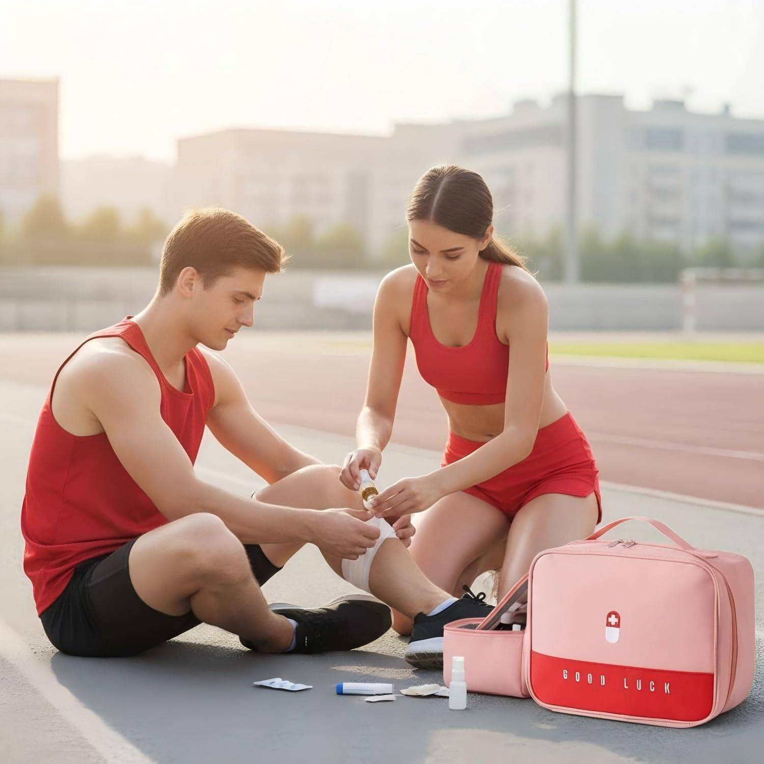 Zwei Athleten in roter Sportkleidung sitzen auf einer Laufbahn, während die Frau das Knöchel des Mannes bandagiert, mit einem Erste-Hilfe-Kasten und medizinischen Versorgungsmaterialien neben ihnen.