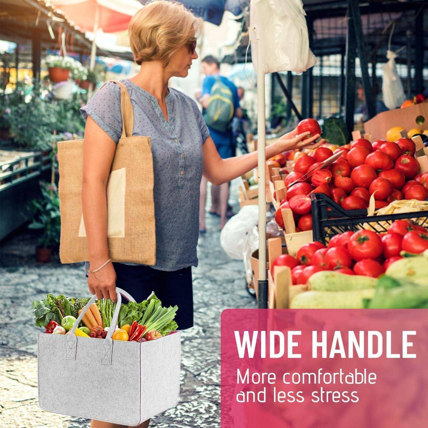 Frau beim Einkaufen auf einem Außenmarkt, die neben einem Schild mit der Aufschrift „BREITER GRIFF Komfortabler und weniger belastend" Tomaten auswählt und eine wiederverwendbare Einkaufstasche trägt.