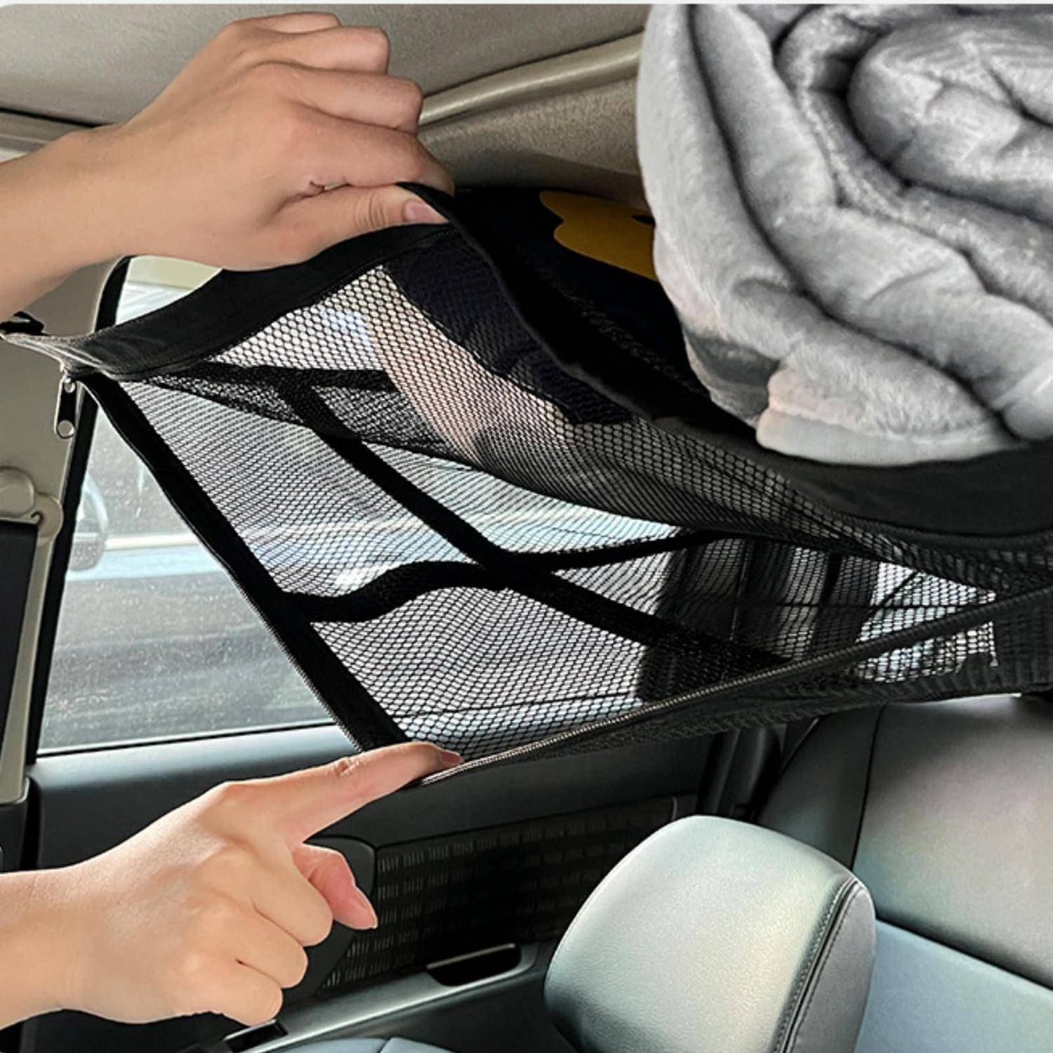 Hände zeigen ein Maschenladungsnetz, das über dem hinteren Bereich eines Autos gespannt ist und eine gefaltete Decke und andere Gegenstände oben sichert.