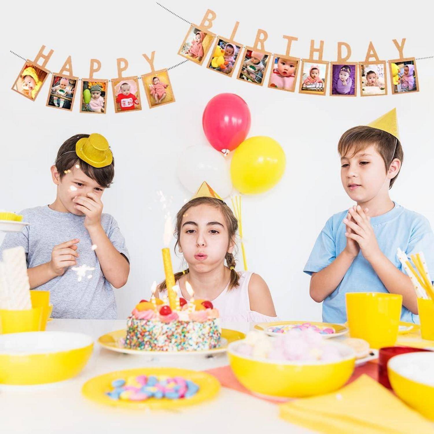 Kinder bei einer Geburtstagsfeier versammeln sich um einen Kuchen mit Kerzen, mit einem Banner 