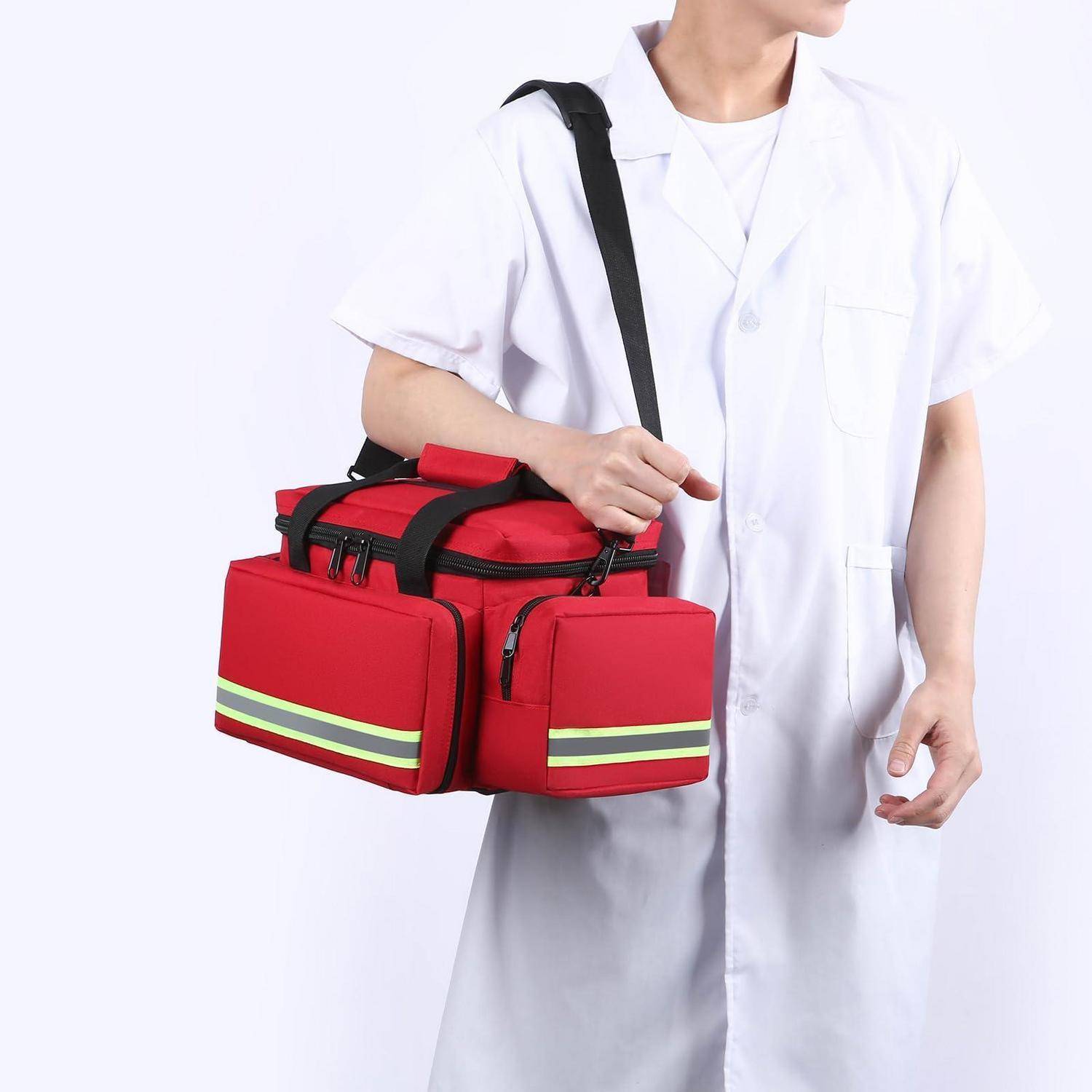Krankenhauspfleger in weißer Uniform, der eine rote isolierte medizinische Liefertasche mit Schultergurt und vorderen Taschen trägt.