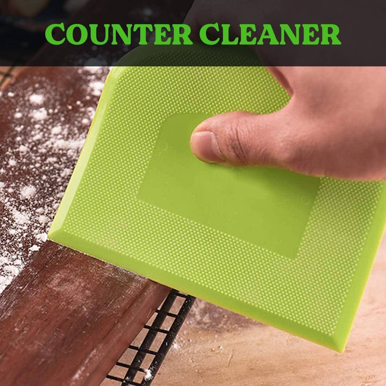 Hand, die ein grünes 'COUNTER CLEANER' Scheuertuch hält und eine staubige Arbeitsplatte oder Regalkante reinigt.