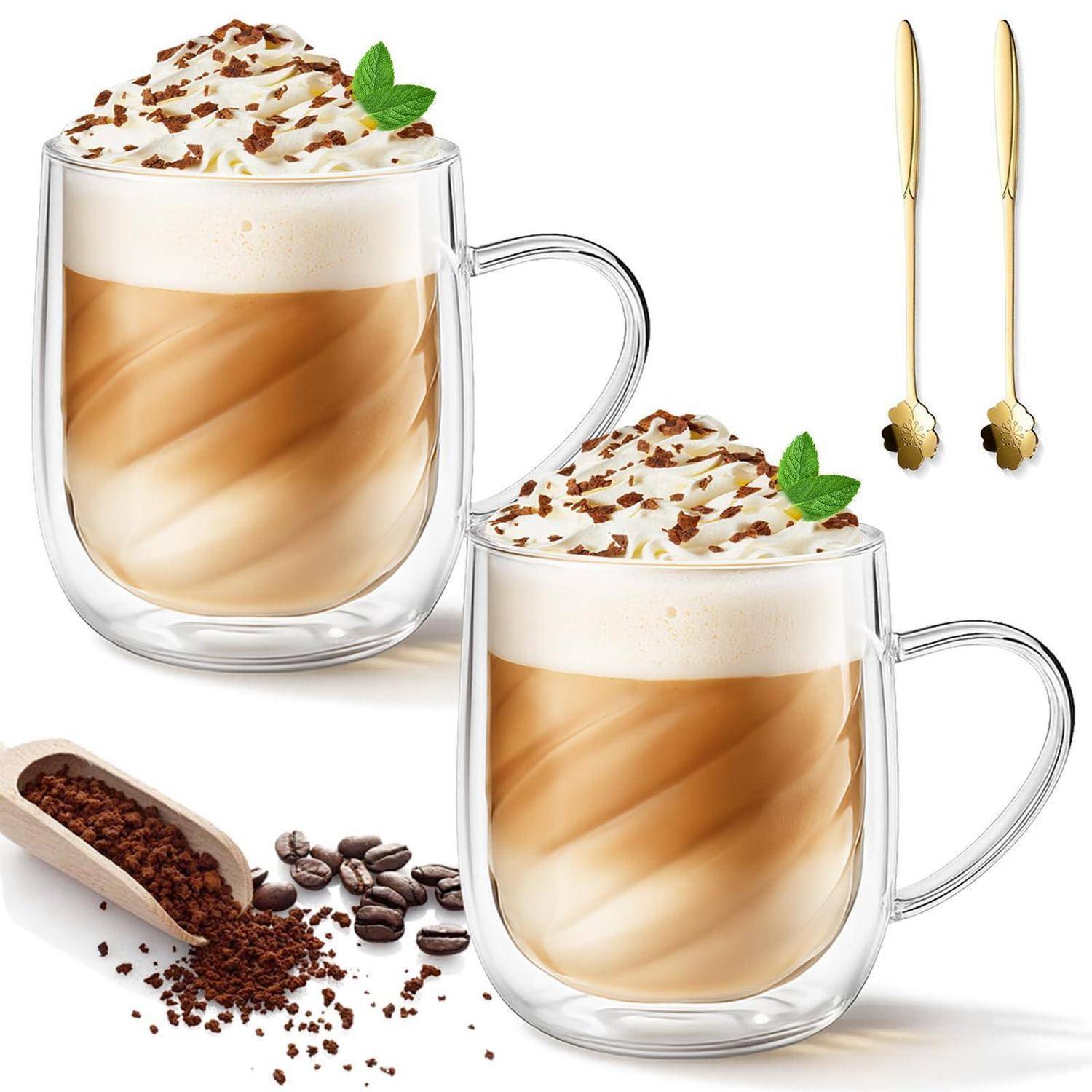 Zwei Glastassen mit geschichteten Kaffeegetränken, gekrönt mit Schlagsahne, Schokoladenflocken und Minze, gezeigt mit goldenen Löffeln und Kaffeebohnen.