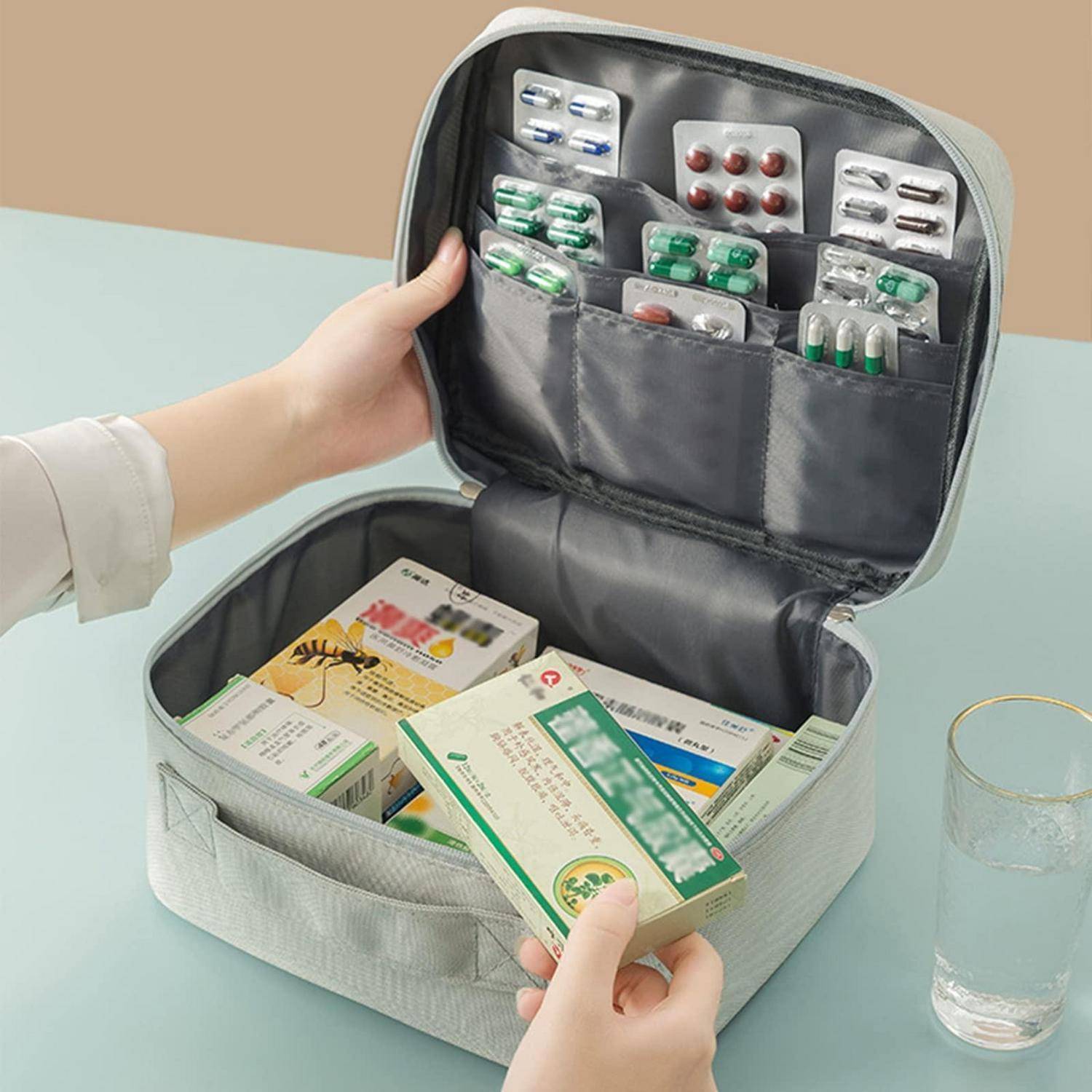 Offene Medikamentenorganizer-Box mit assotierten Blisterpackungen und Medikamentenboxen, mit einem Wasserglas in der Nähe.