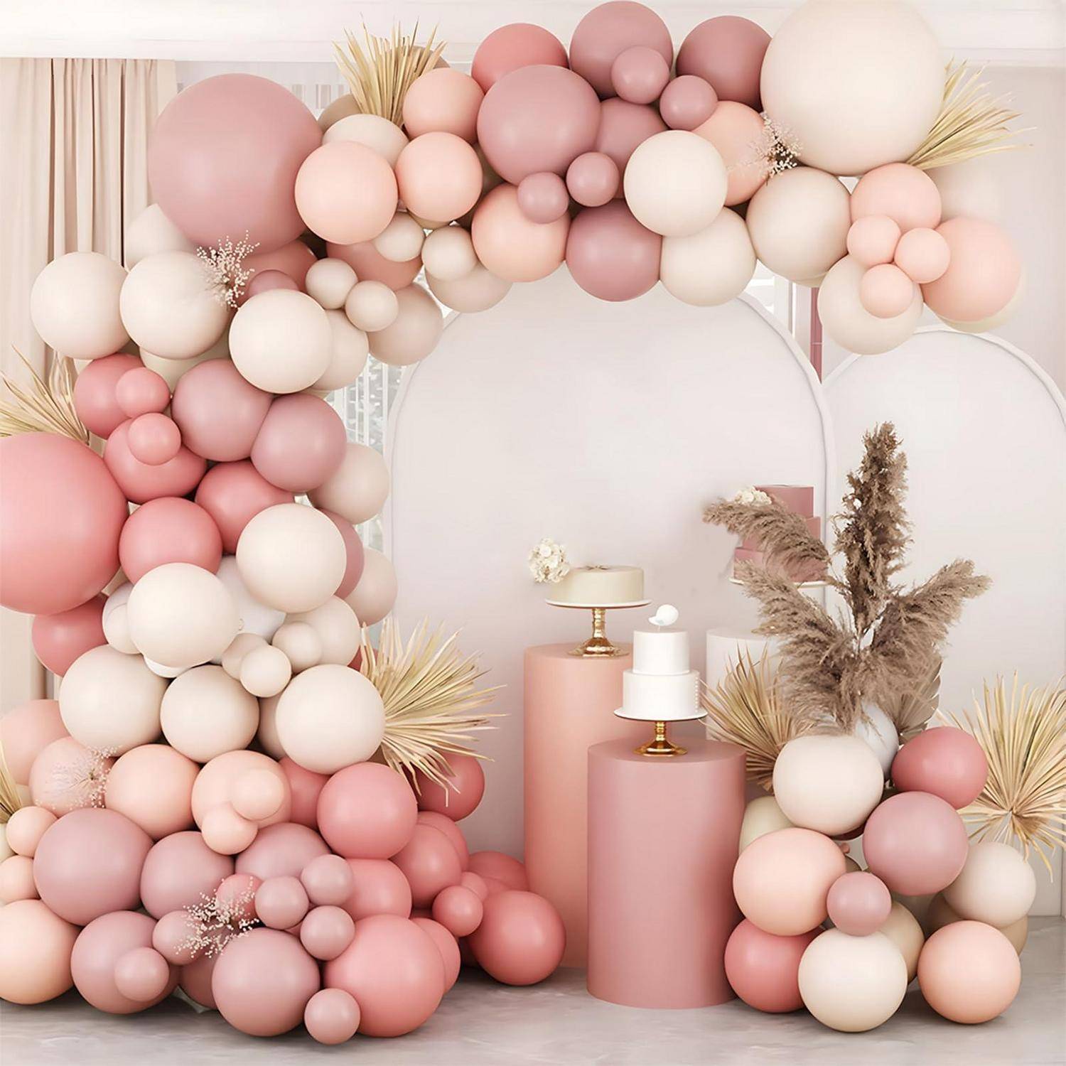 Pastellrosa- und cremefarbener Ballonarc mit passenden Sockeltorten und Trockenblumenarrangement, gestaltet als festliche Partydessertdekoration.