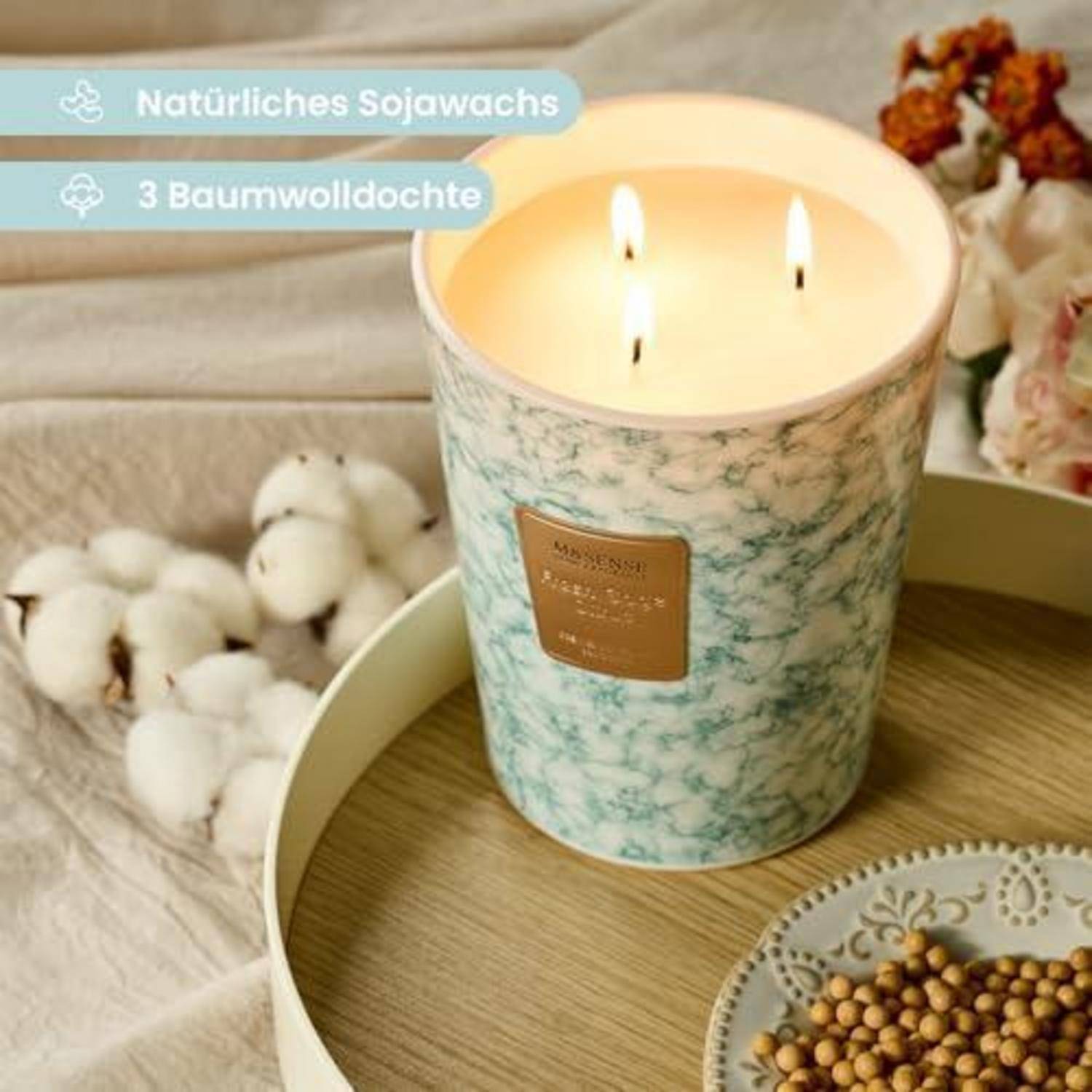 Beleuchtete Sojawachskerze in einem marmorierten türkisfarbenen Becher auf einem Tablett, beschriftet mit „Natürliches Sojawachs" und „3 Baumwolldochte"" (natürliches Sojawachs, 3 Baumwolldochte).