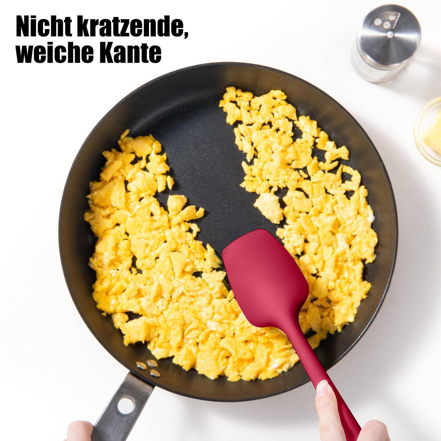 Draufsicht-Foto von Rühreiern in einer Pfanne, die mit einem Spatel geschoben werden; deutscher Text besagt „Nicht kratzende, weiche Kante