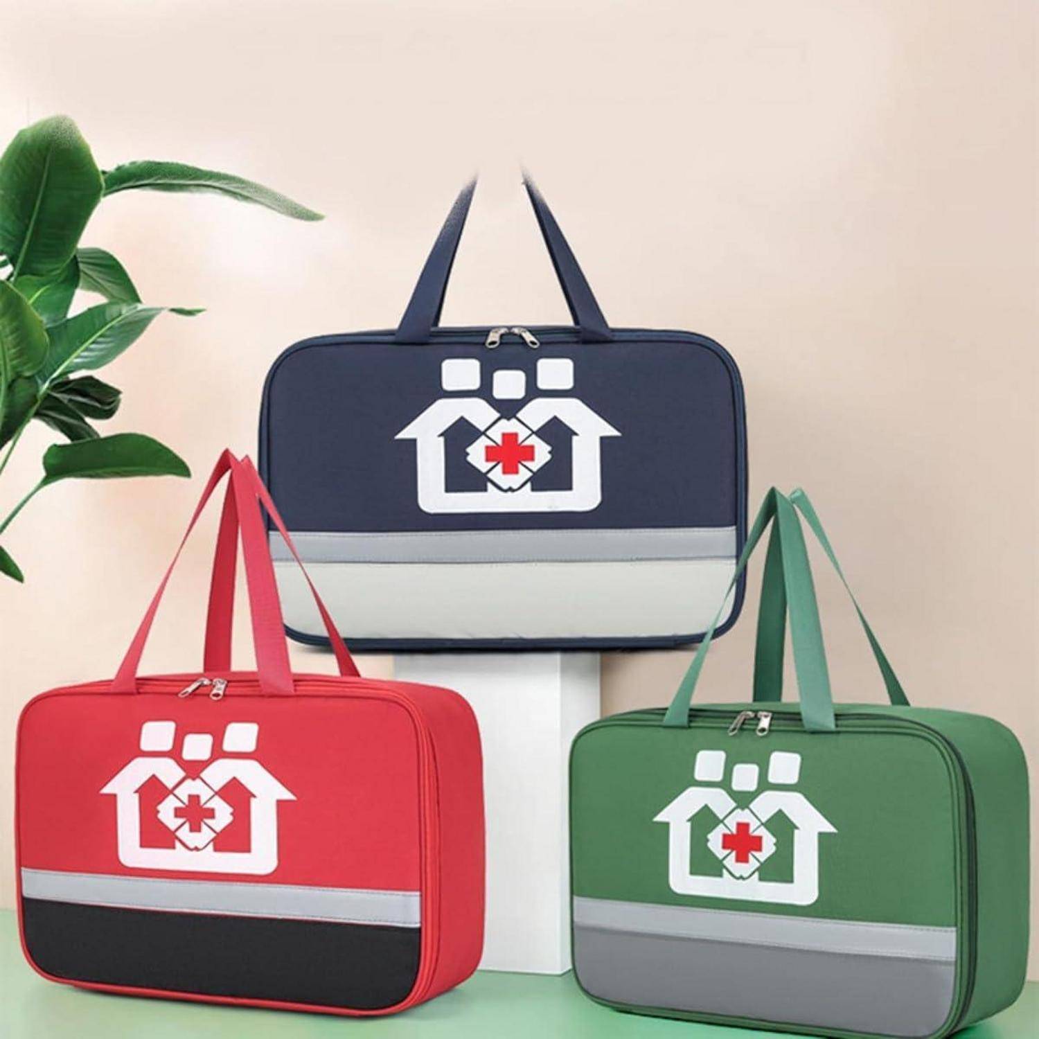 Drei medizinische Erste-Hilfe-Taschen in Marineblau, Rot und Grün mit weißen Kreuzhaus-Logos, angeordnet vor einer Schachtel neben einer Pflanze.