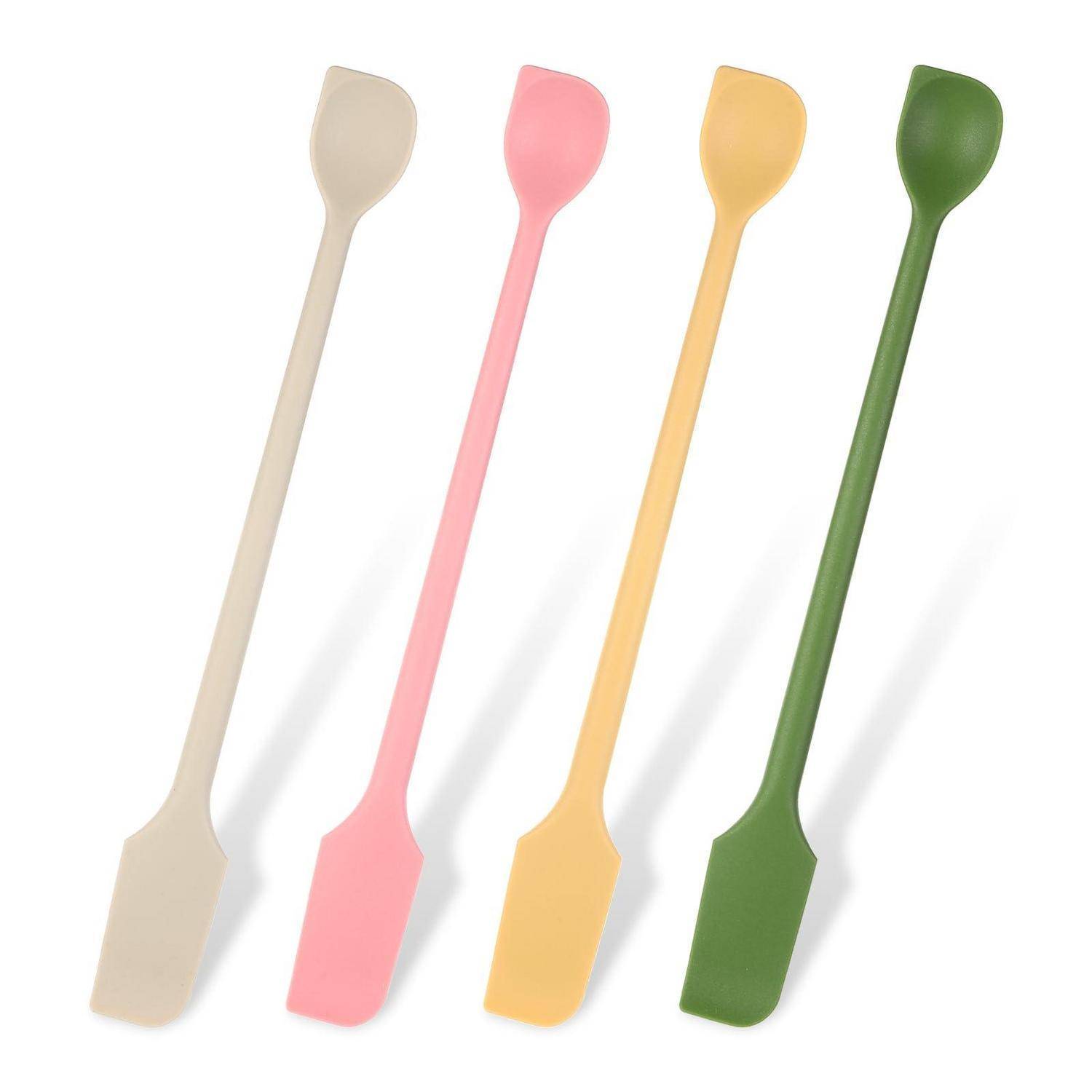 Vier bunte Silikonspachteln oder Rührlöffel diagonal auf weißem Hintergrund angeordnet: beige, rosa, gelb und grün.