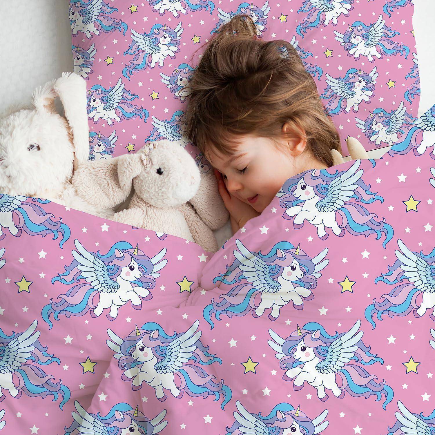 Junges Mädchen, das in einem Bett mit rosa Einhorn-Muster schläft, mit zwei weißen Kuscheltieren neben ihr.