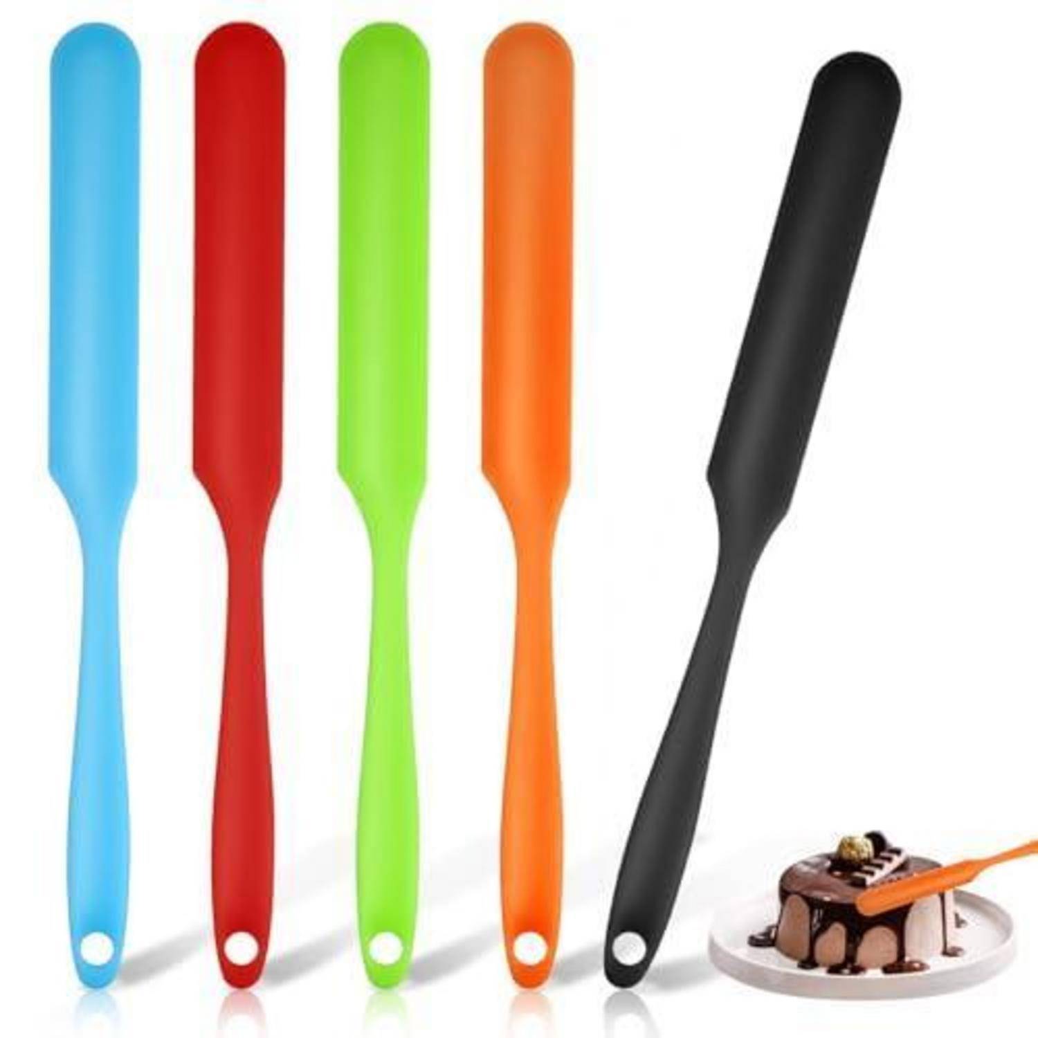 Satz farbenfroher Silikonspachteln, die aufrecht stehen, mit einem schwarzen Spachtel, der schräg neben einem kleinen Dessert angewinkelt ist, das auf einem Teller serviert wird.