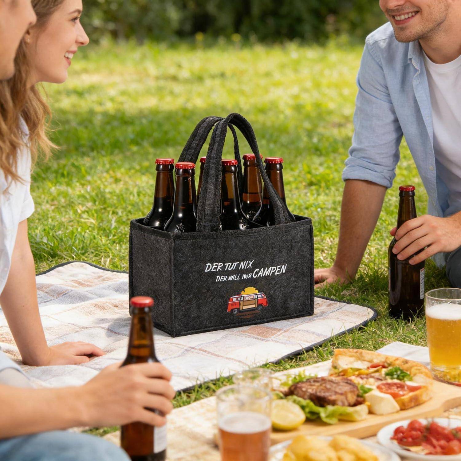 Freunde, die im Freien picknicken, mit einem Filz-Bierträger mit der Aufschrift „DER TUT NIX DER WILL NUR CAMPEN