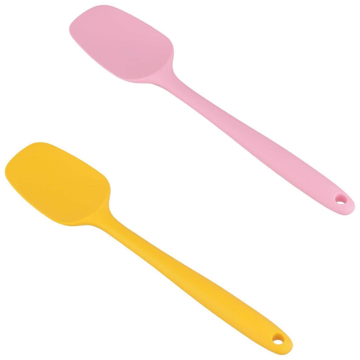 Zwei Silikonspachtel, einer rosa und einer gelb, diagonal auf weißem Hintergrund dargestellt.