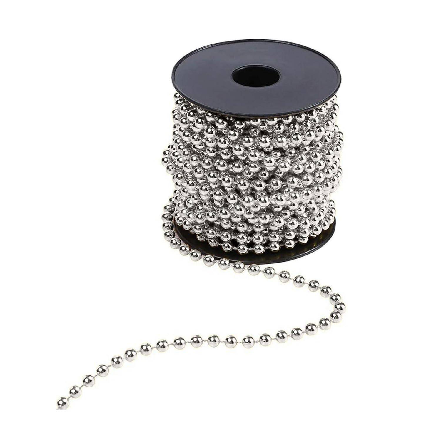 Eine Spule mit silberner metallischer Perlenkette mit loser Kette, die auf weißem Hintergrund herausragt.