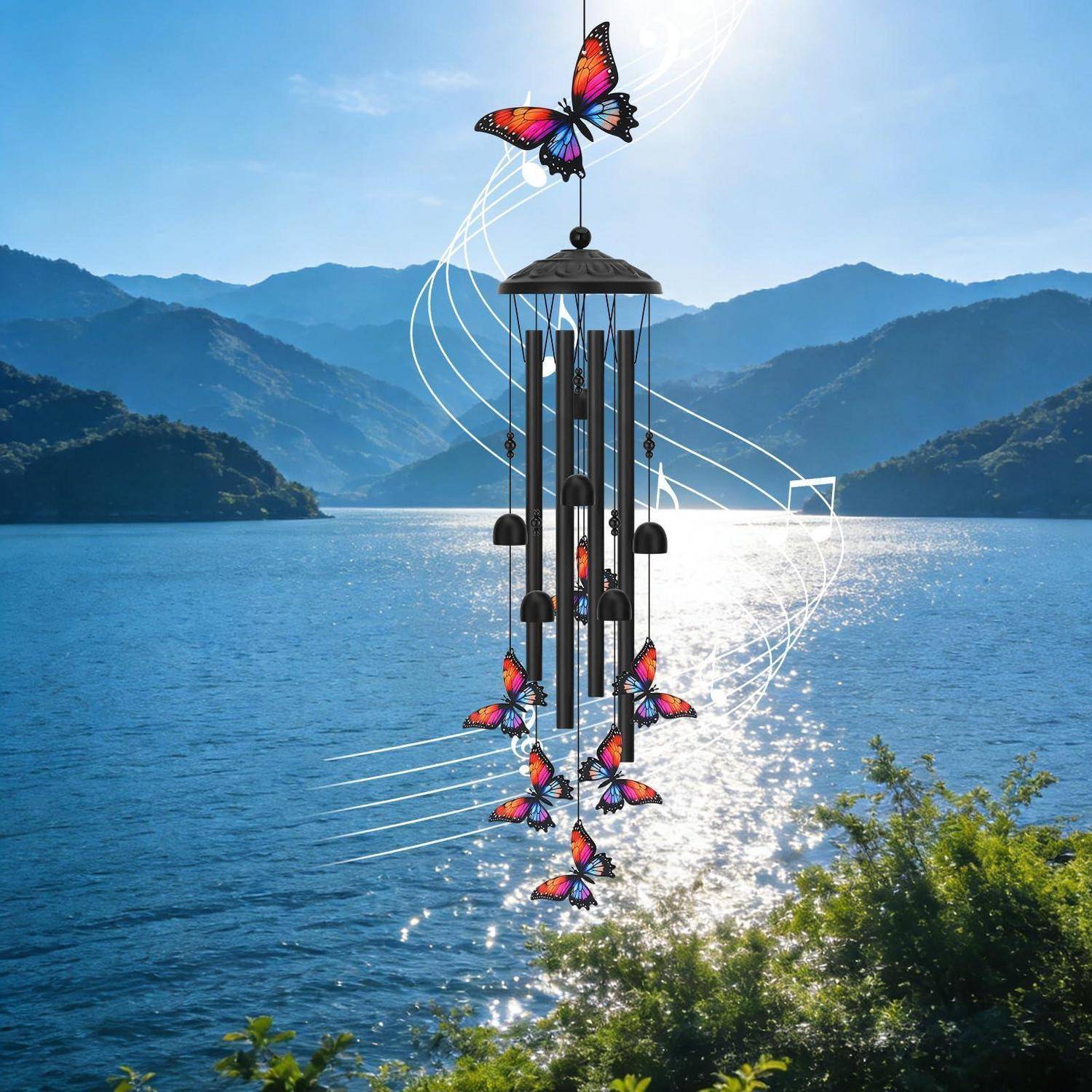 Eine schmetterlingsthematische Windglocke hängt über einem sonnenbeschienenen See mit Bergen im Hintergrund.
