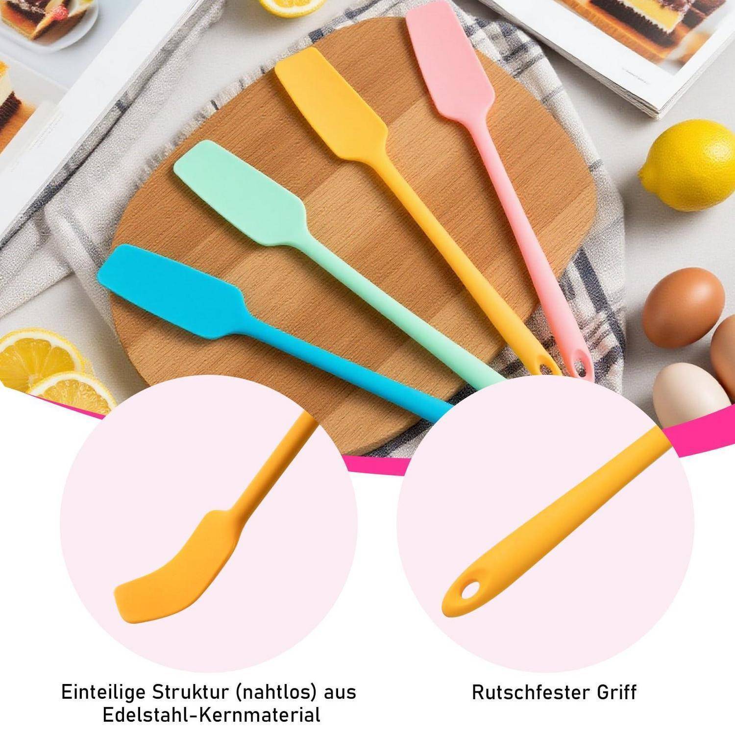 Satz farbiger Silikon-Spatel auf einem Holzbrett mit Eiern, Zitrone und Backzubehör; deutsche Etiketten besagen nahtloser Edelstahlkern und rutschfester Griff.